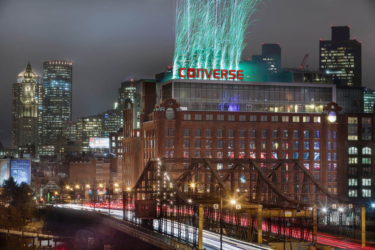 Converse Boston head quarters at night with firework display behind the main signage on top of the building. opening night of HQ
