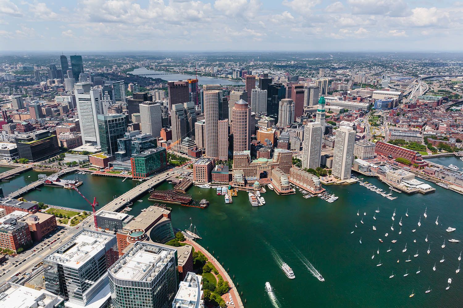 Architectural aerial photograph of Boston city with the harbor in the foreground and boats coming and going on a summers day