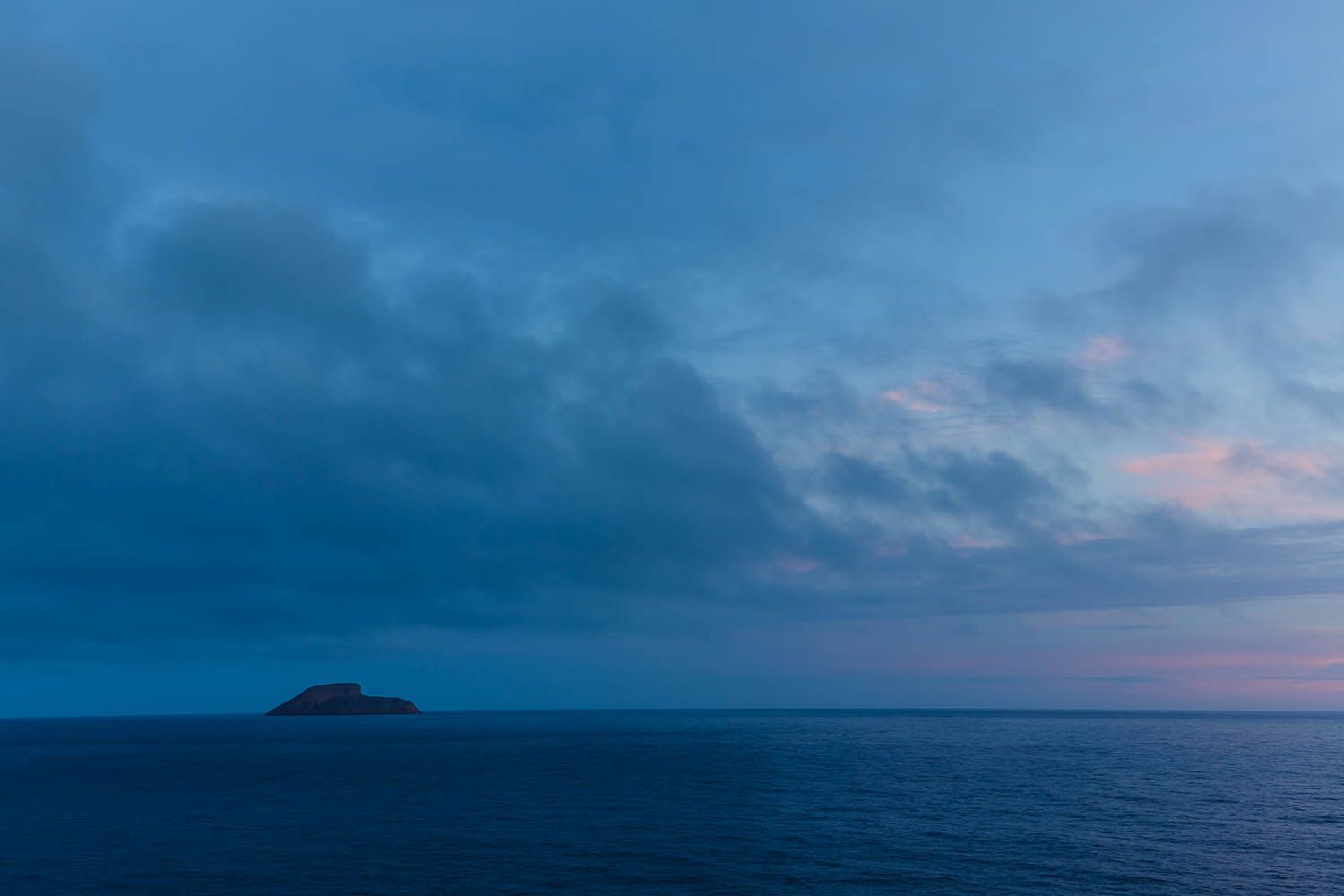 Color landscape photograph of Terceira Island in the Azores Portugal, showing wide angle view of small island off coast taken after sunset