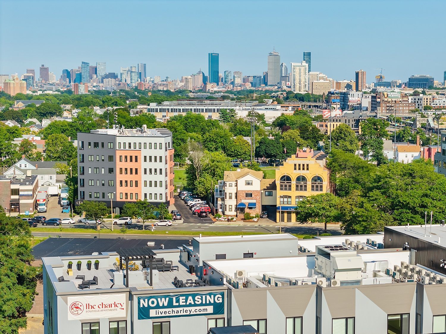 AN ARCHITECTURAL STYLE DRONE PHOTOGRAPH SHOWING THE LOCATION OF A NEW RESIDENTIAL COMPLEX IN RELATION TO THE CITY OF BOSTON IN BACKGROUND