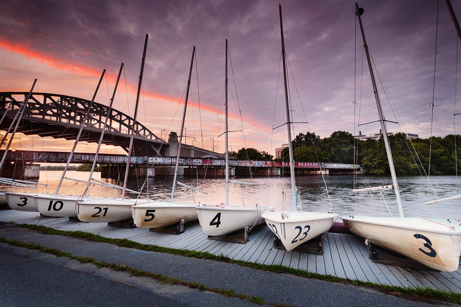 Boston color landscape photograph of boats moored along the Charles River, taken at dusk to show colorful sky and BU bridge in background