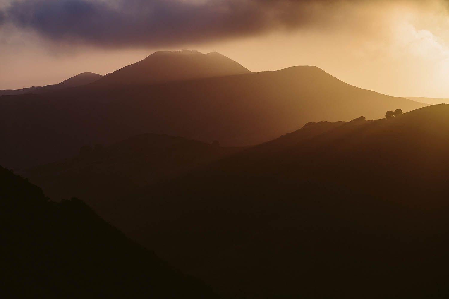 Color landscape photograph taken near San Francisco in California showing mountain silhouette with the sunset in the background