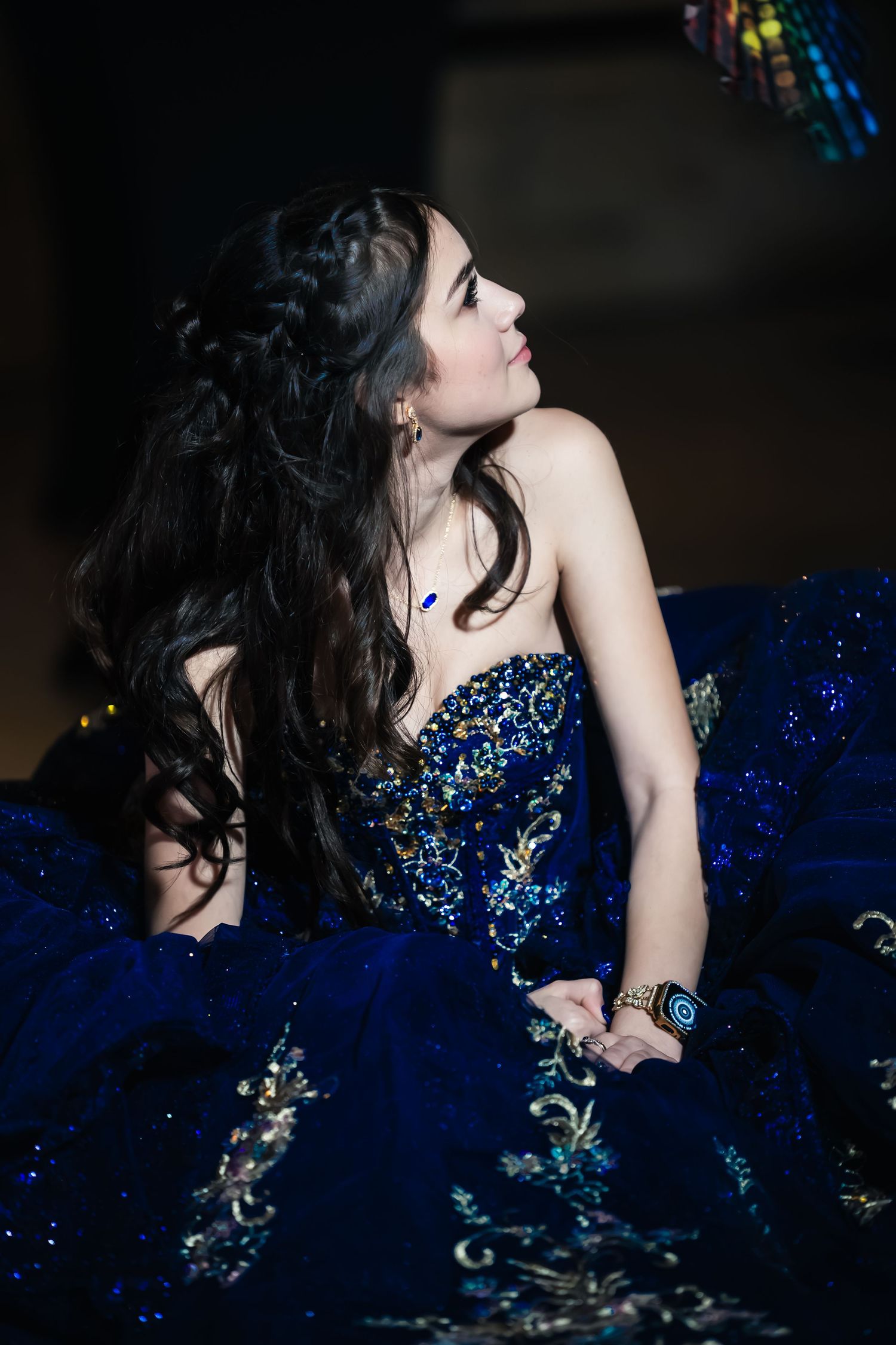 A person in a dark blue sequined dress leans back gracefully in a dramatic dance pose against a black background.