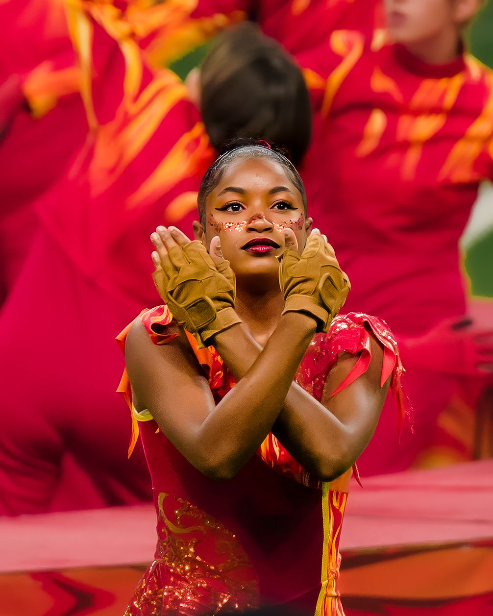 Performer in vibrant red and yellow costume shows joyful expression while dancing during cultural performance.