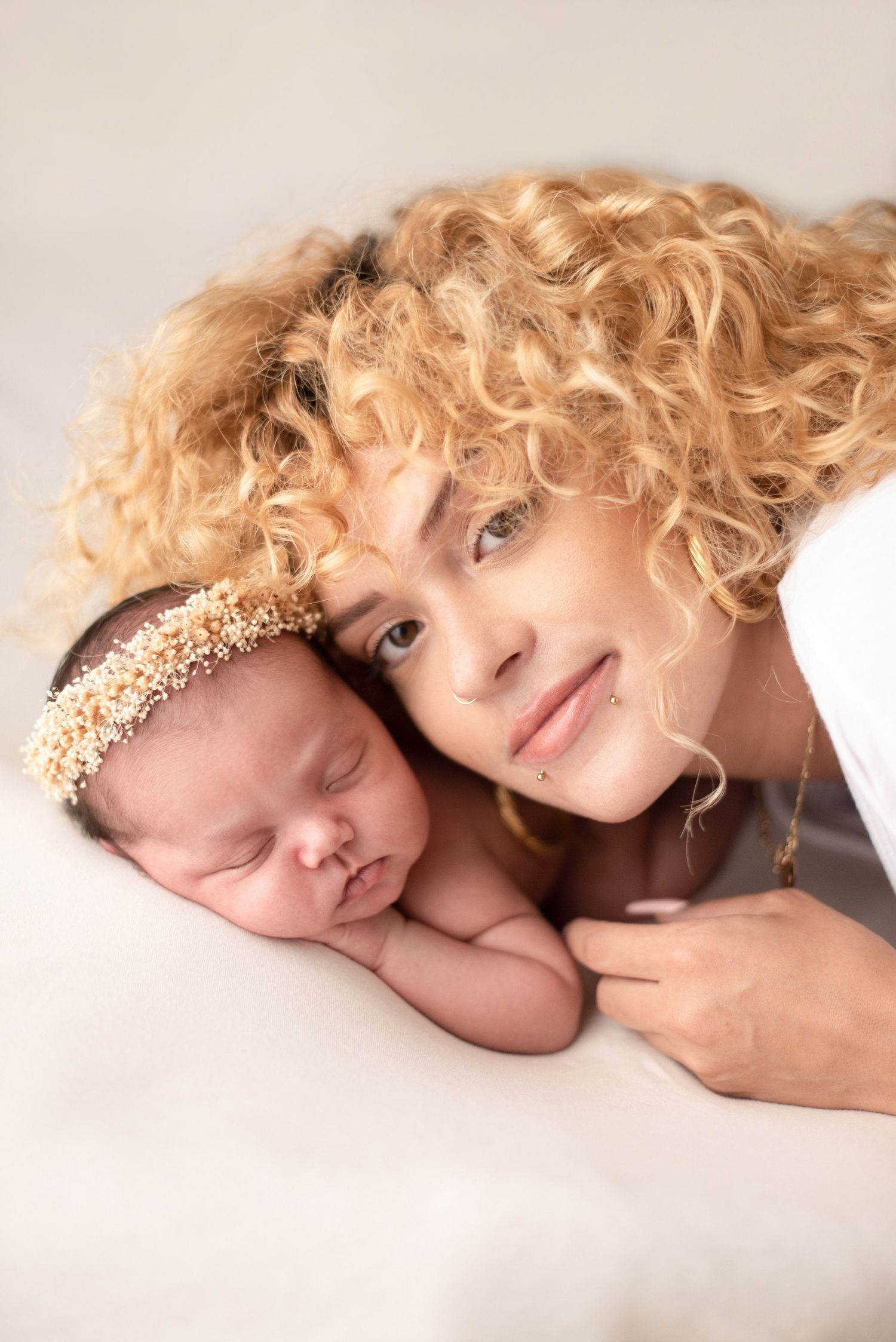 Sweet portrait of parent and sleeping baby with matching pearl headbands.