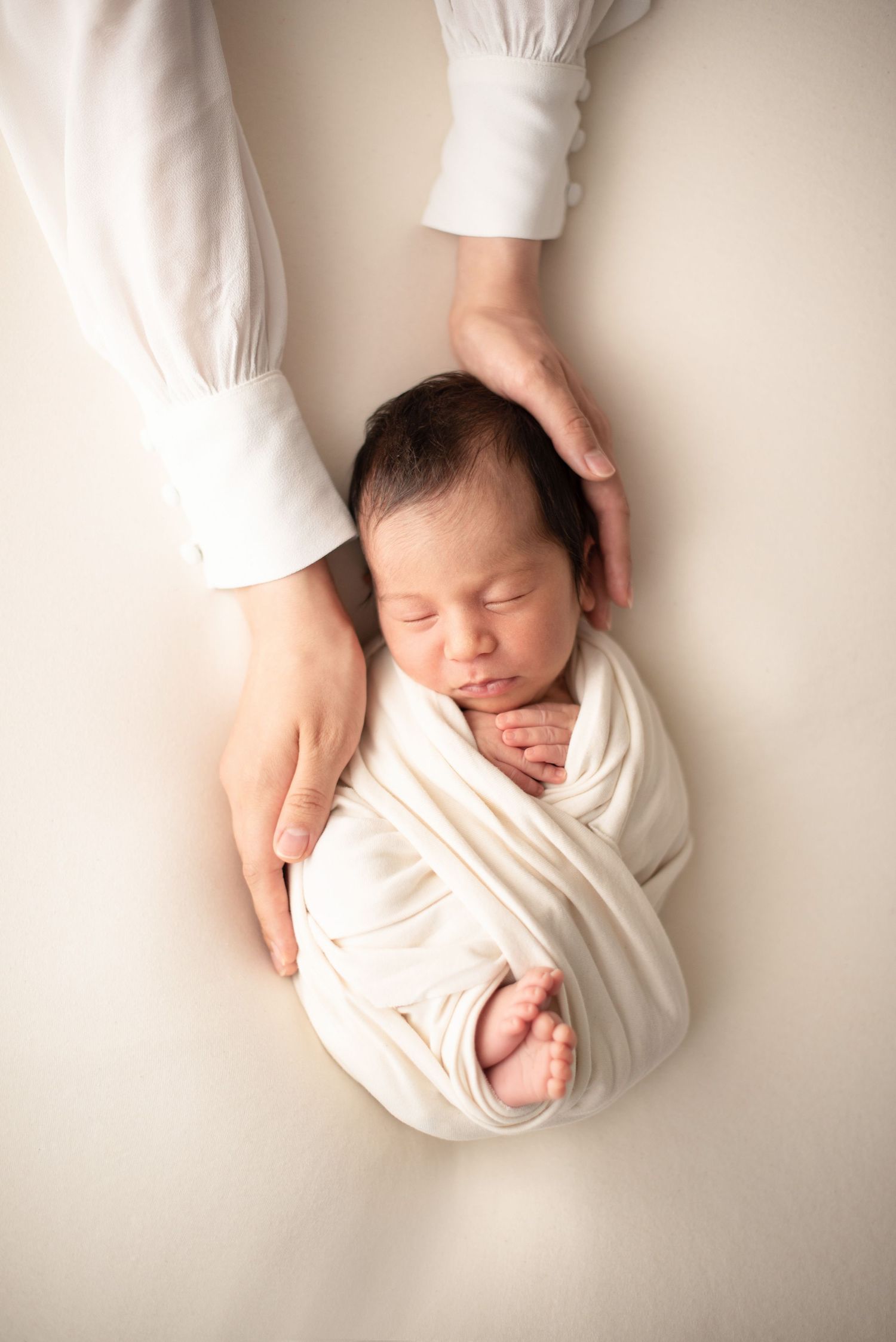 Newborn baby peacefully sleeping while wrapped in soft white fabric.