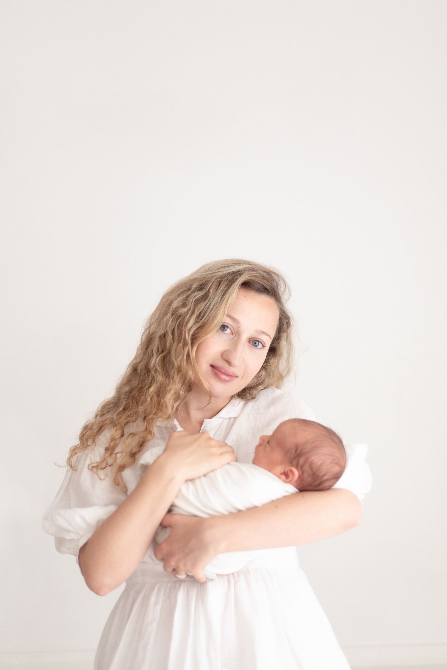 Professional mother and newborn portrait against soft white backdrop.