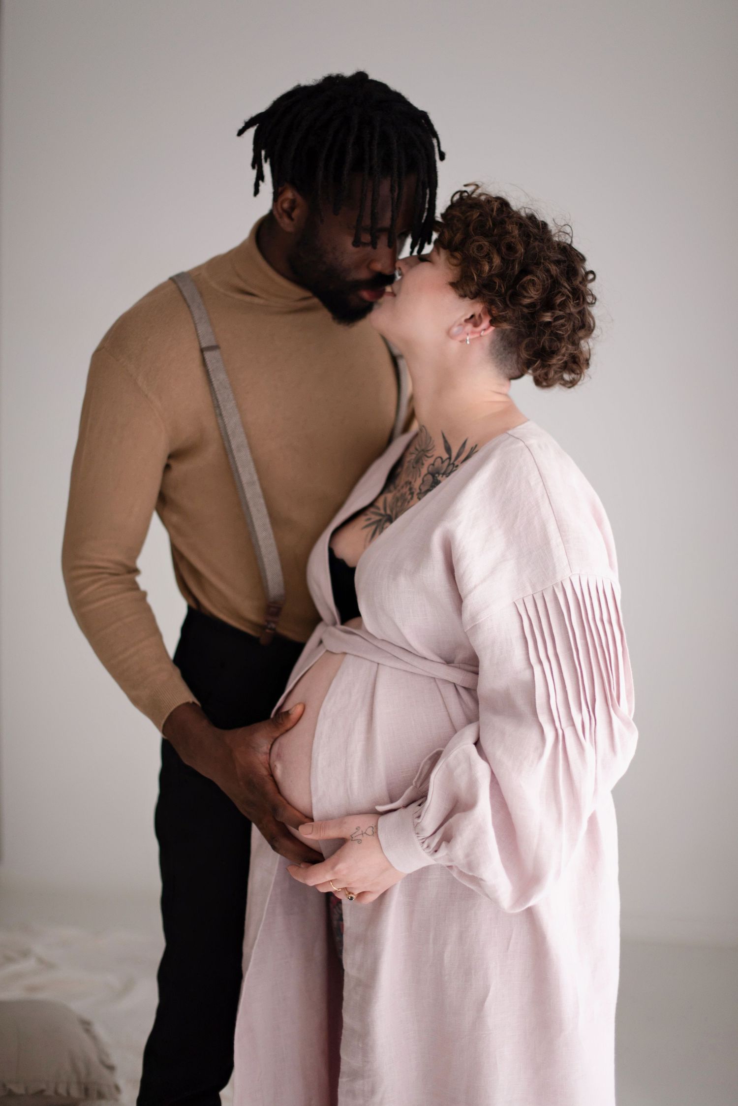 Intimate maternity portrait of couple in elegant attire sharing loving moment.