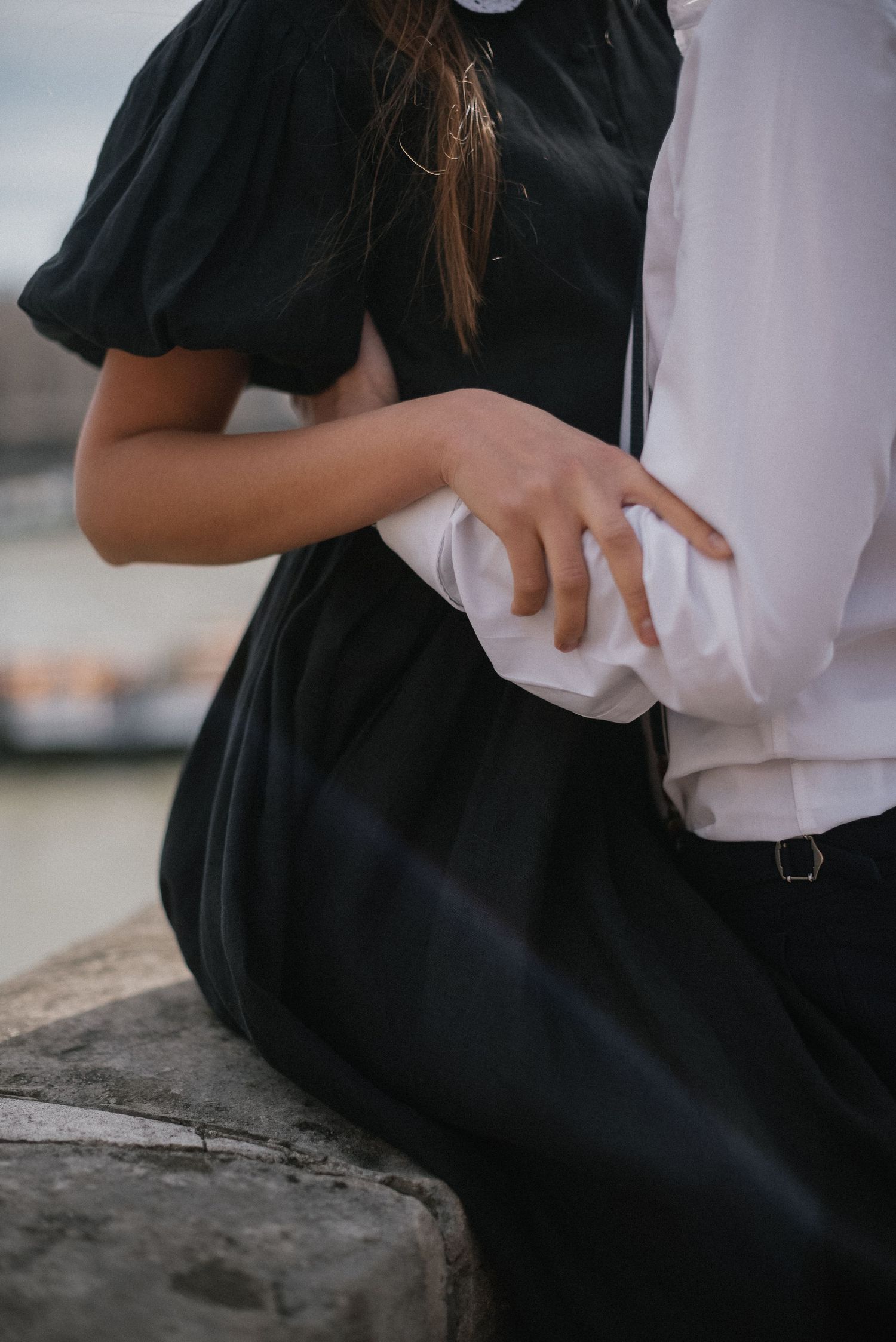 Close-up of hands touching against white clothing and black fabric.