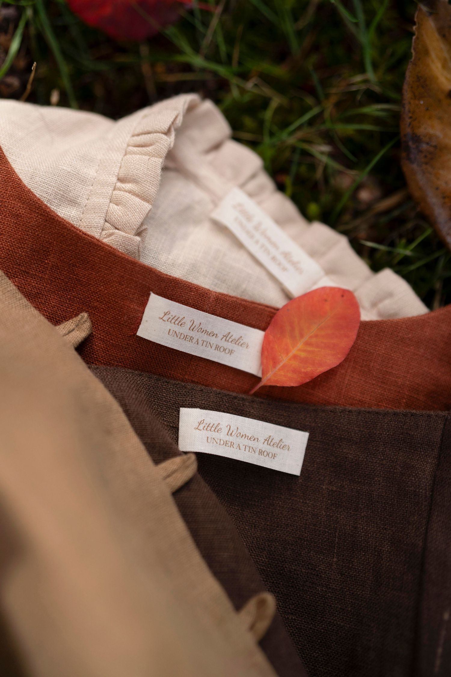 Clothing tags and fabric details with autumn leaves against natural backdrop.