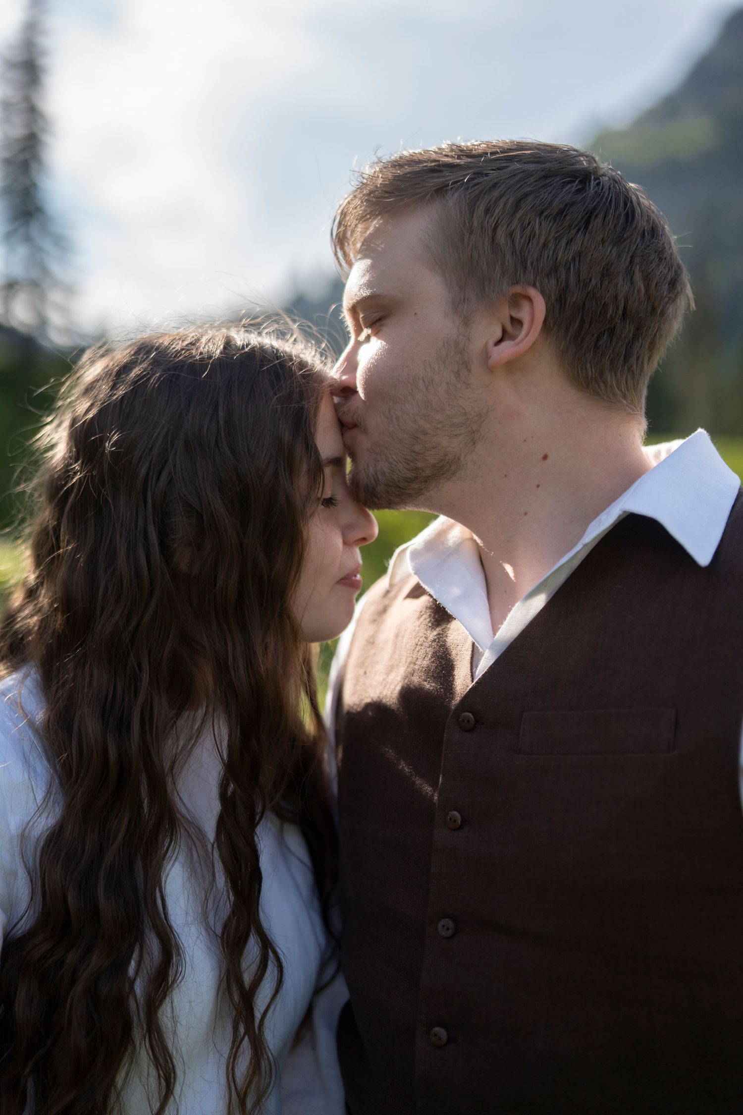 A romantic couple shares an intimate kiss outdoors in a series of four connected photos.
