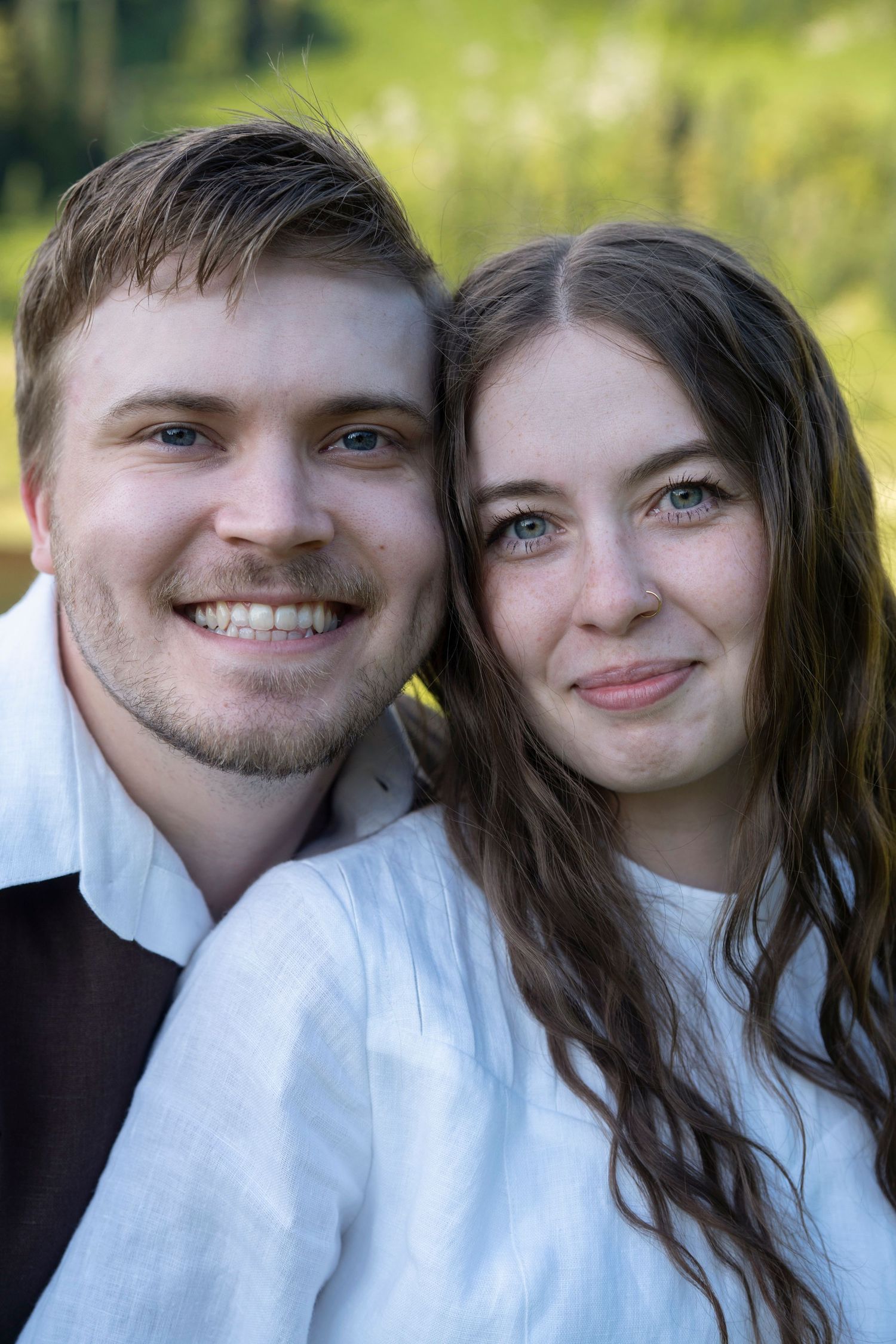A couple in white clothing smiles together in a series of candid outdoor portrait photos.