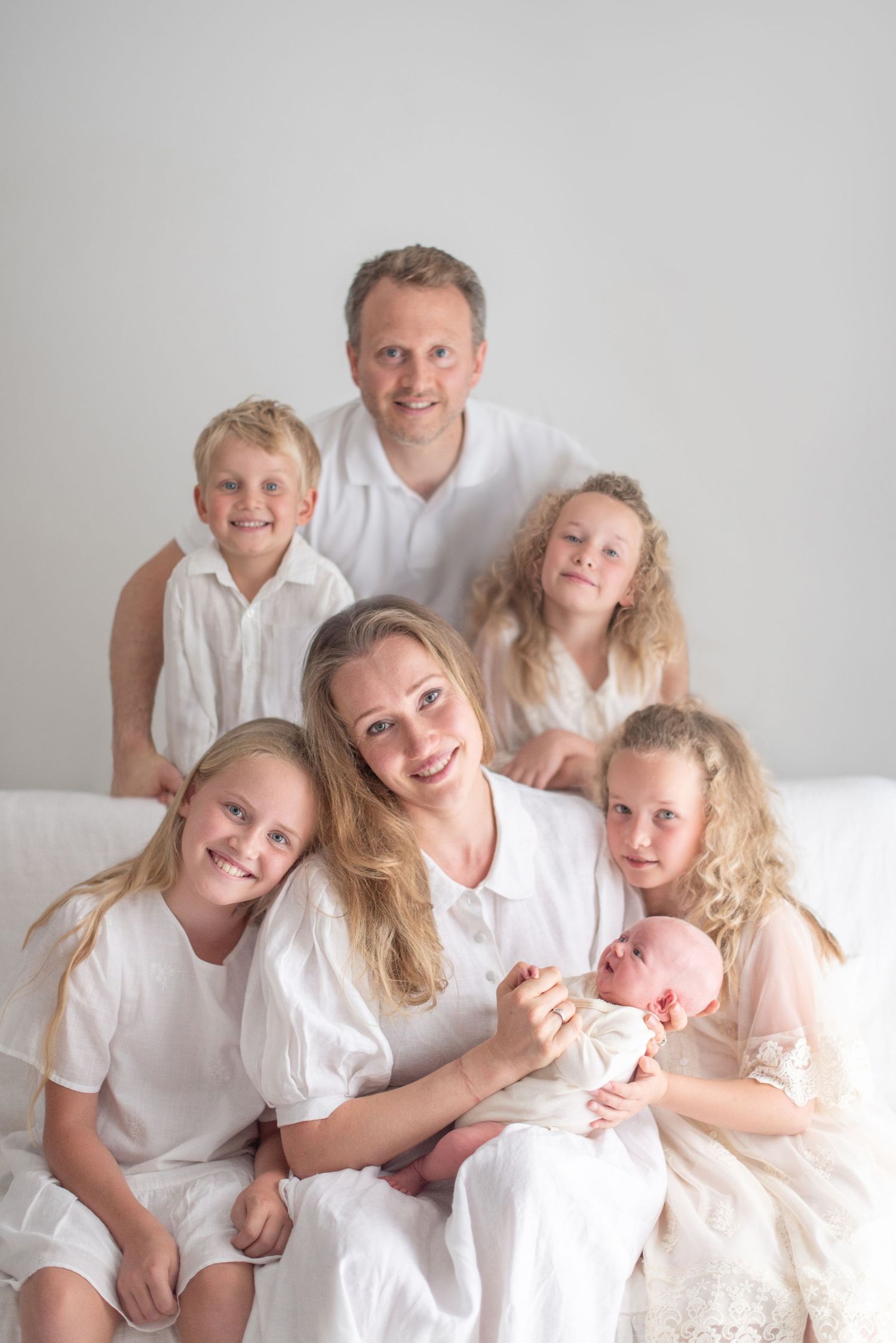 Family portrait in white clothing against light background.
