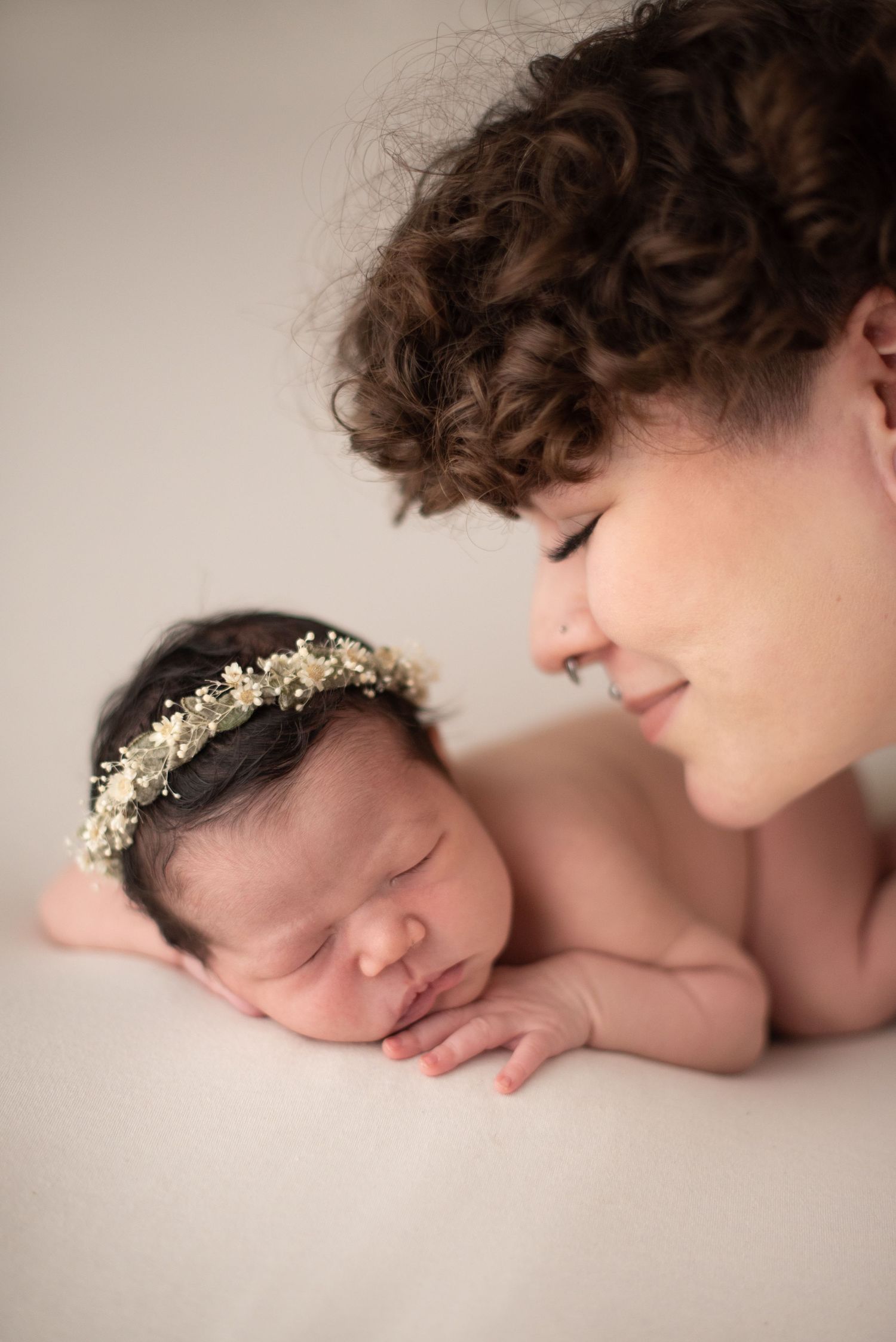 Tender moment captured during professional newborn photography session with soft neutral backdrop.
