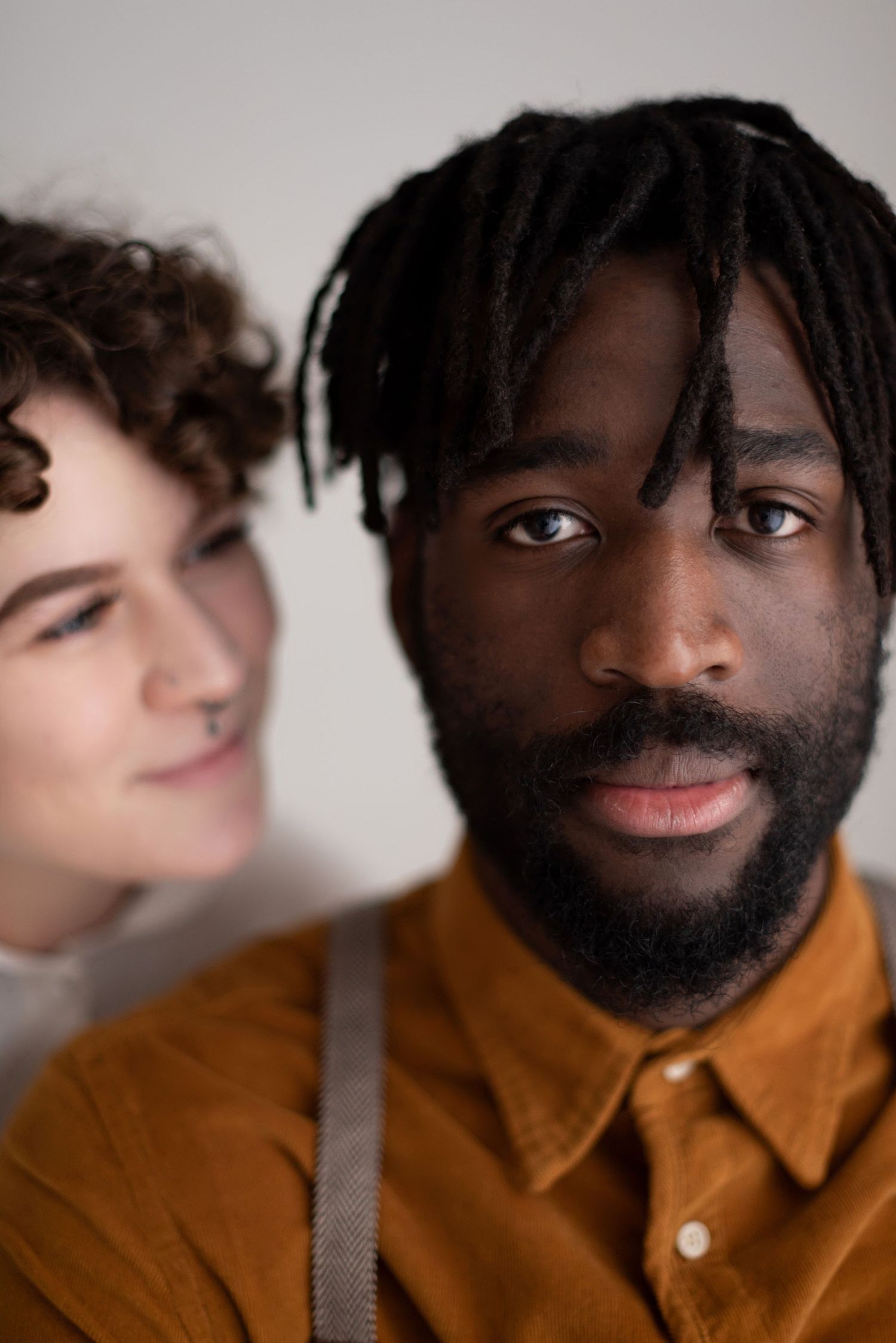 A couple smiles together in an intimate portrait against a light background.