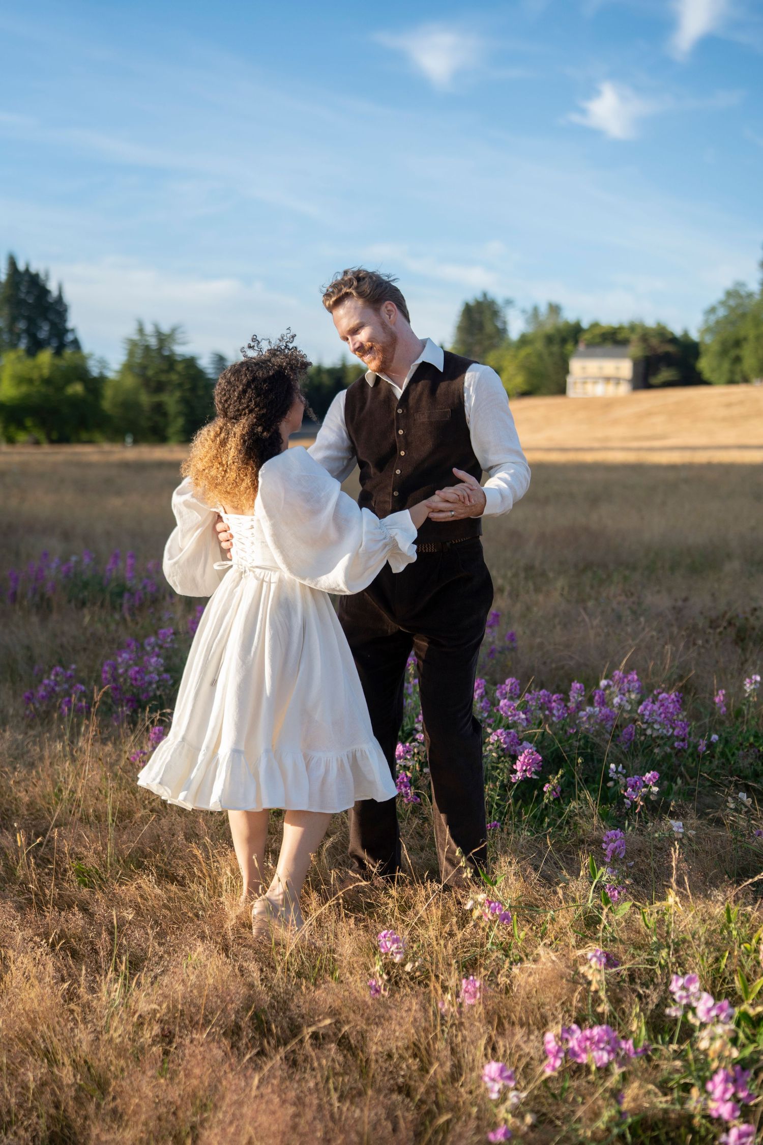 Couple shares romantic moments in a golden field with wildflowers during a beautiful summer photoshoot.