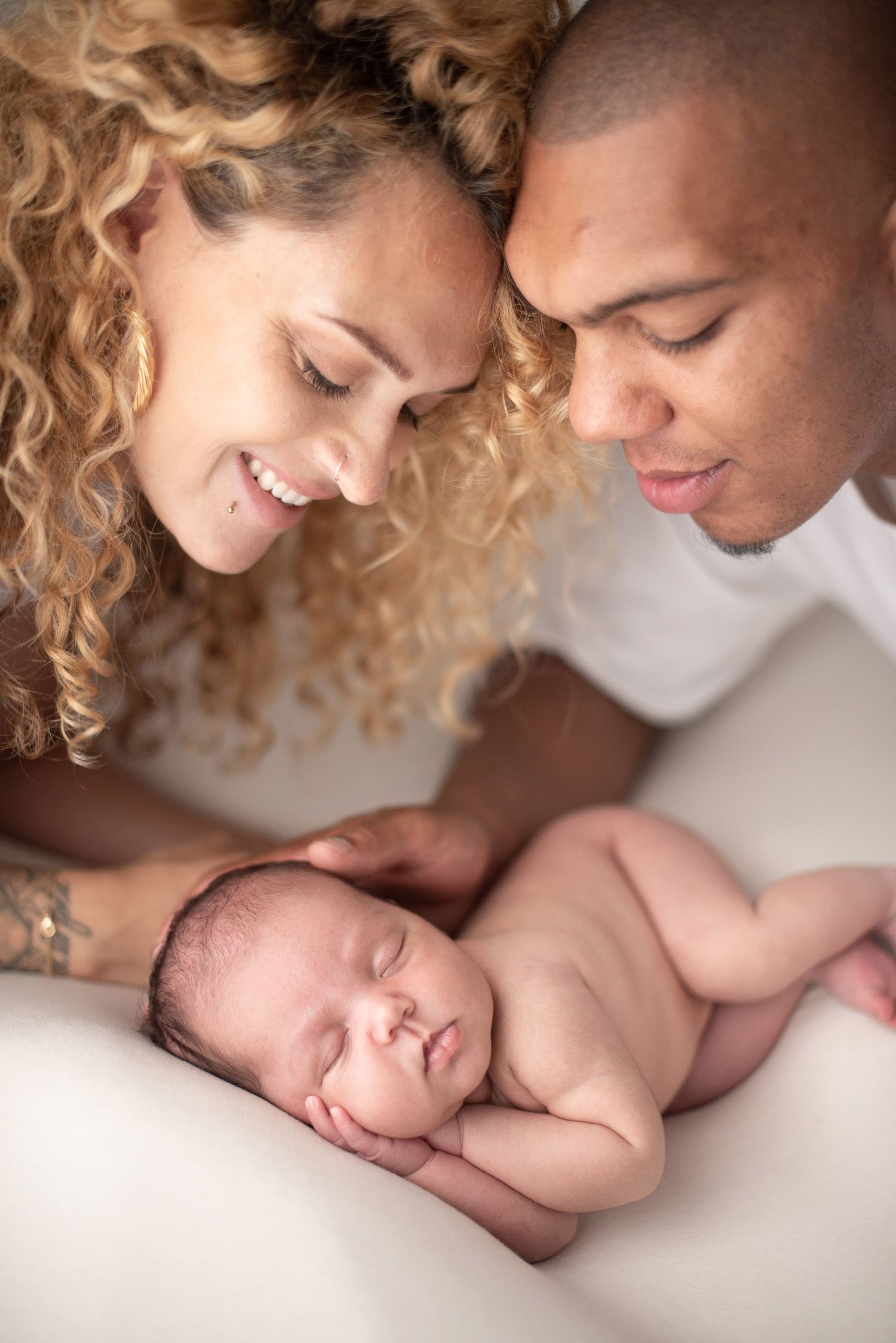 Parents lovingly gazing at their sleeping newborn in intimate family portrait.
