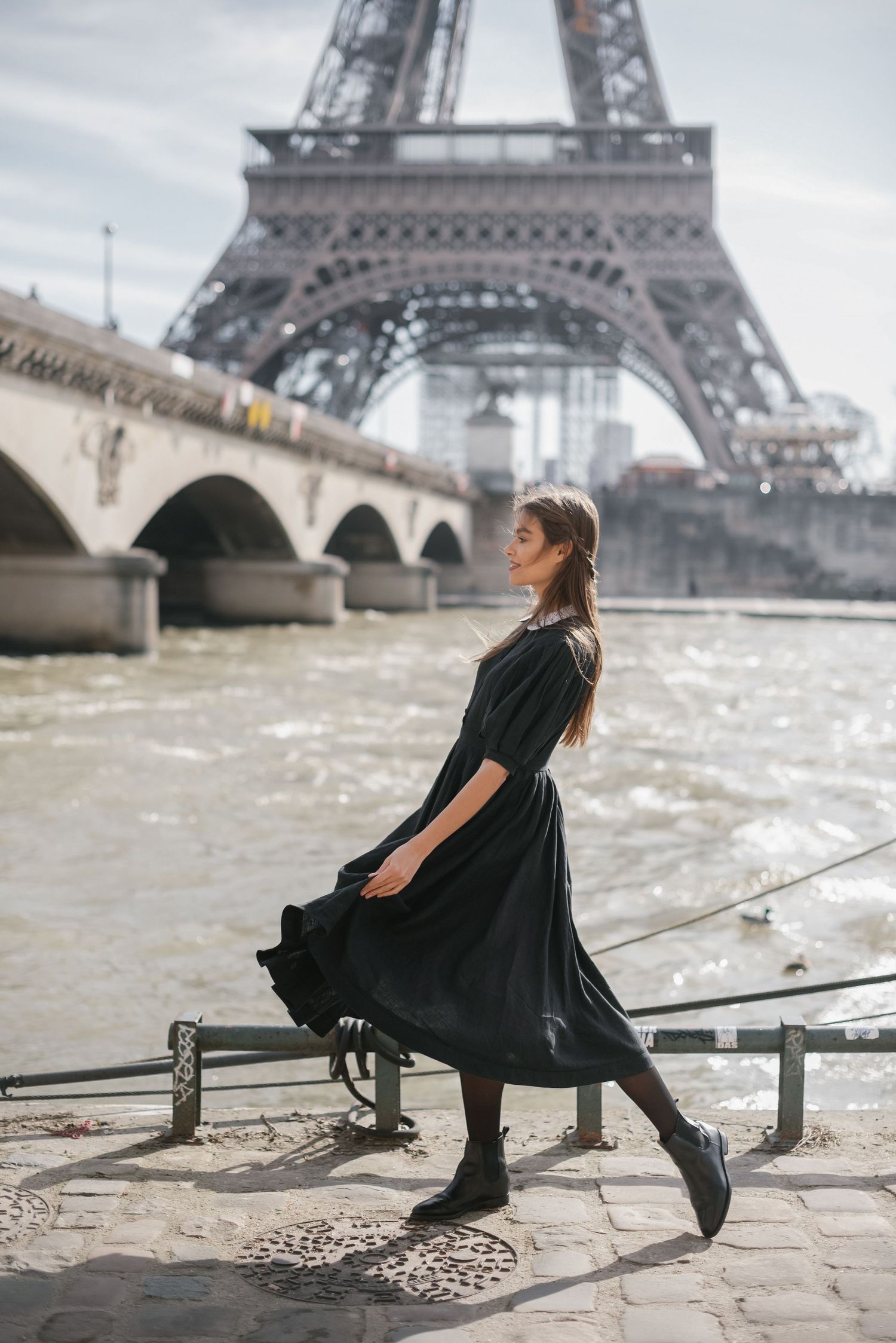 A flowing black dress twirls against the backdrop of the Eiffel Tower.