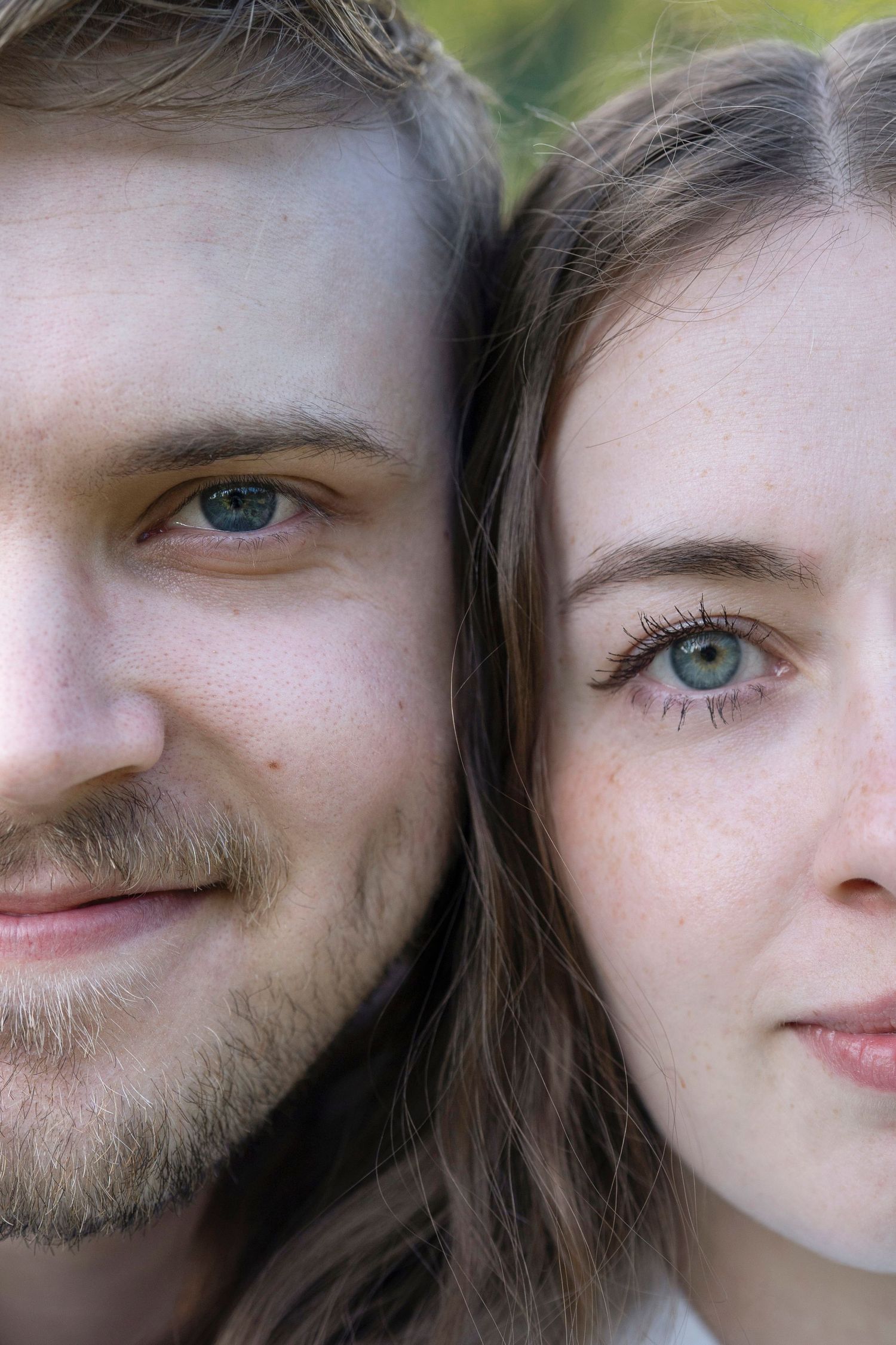 Close up portrait of two faces with bright green eyes looking at camera in natural lighting.