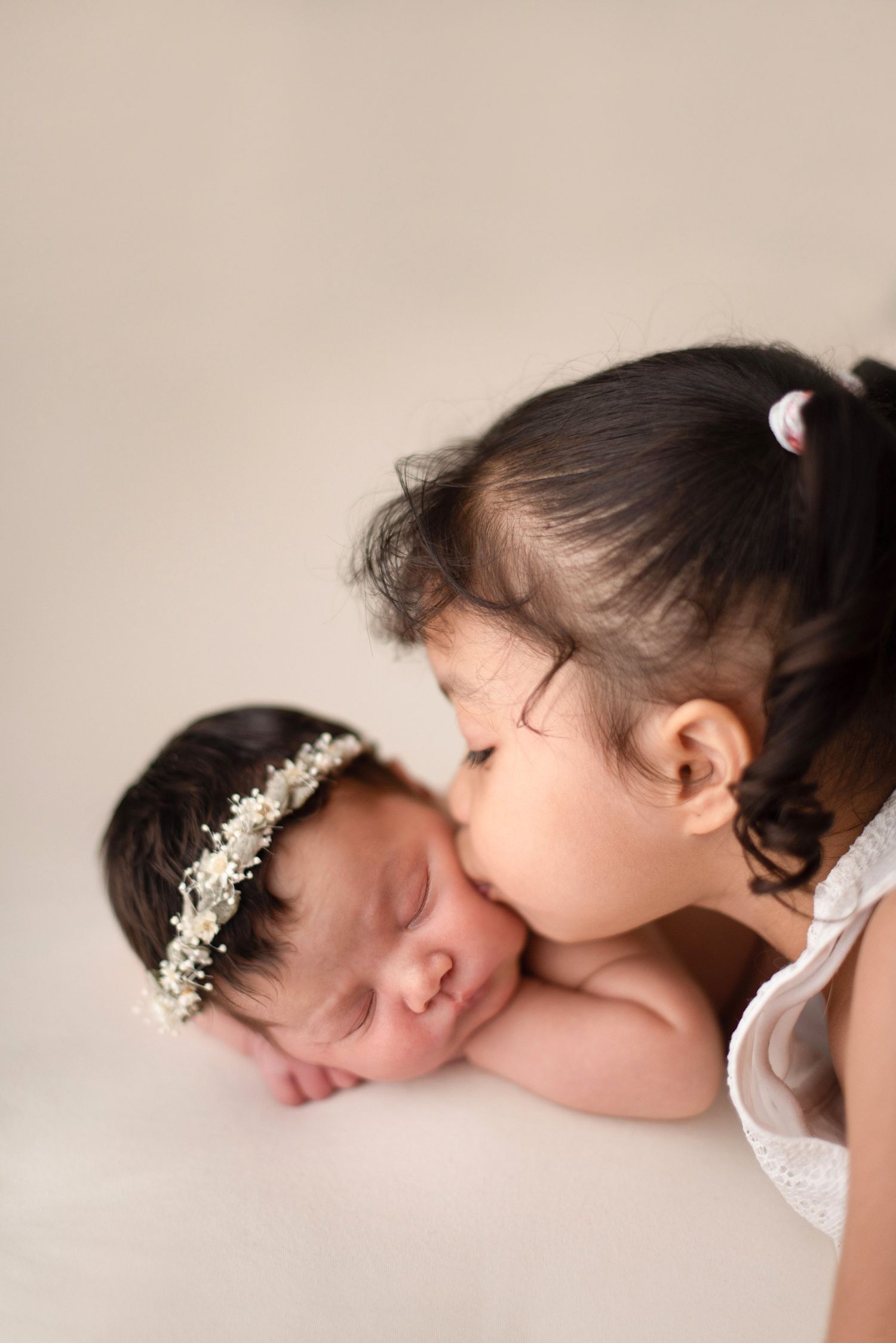 Sweet sibling moment with newborn in delicate crown during professional portrait session.