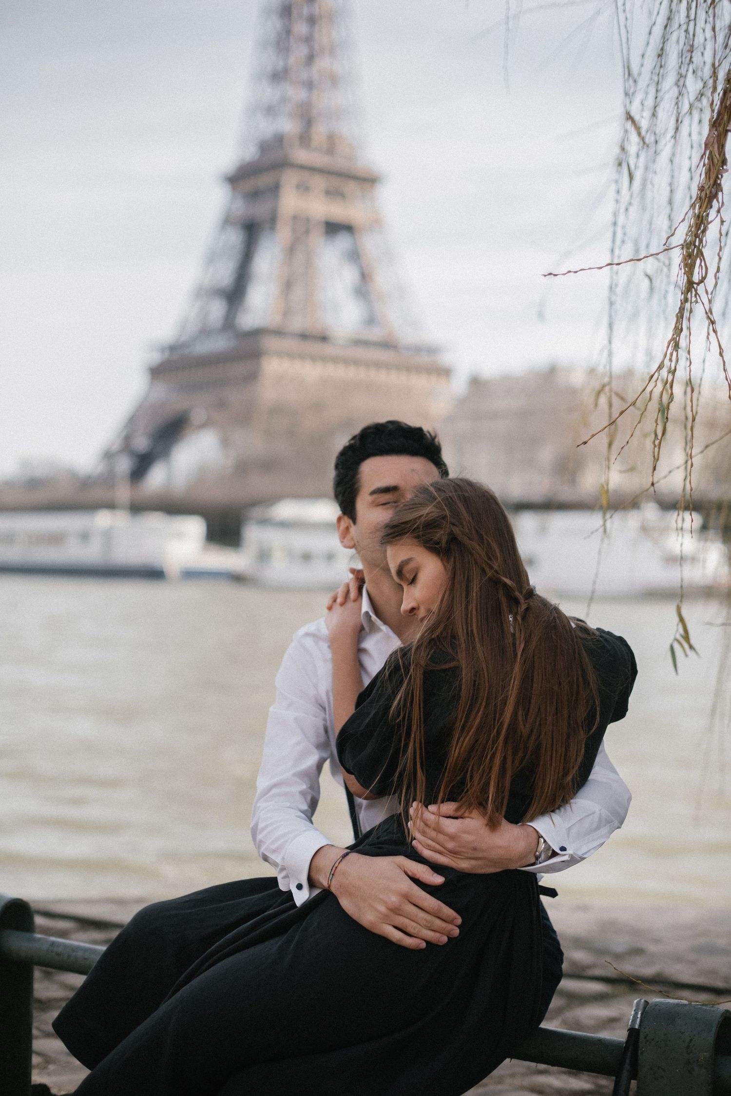 An intimate embrace near the Seine River with the Eiffel Tower in the background.