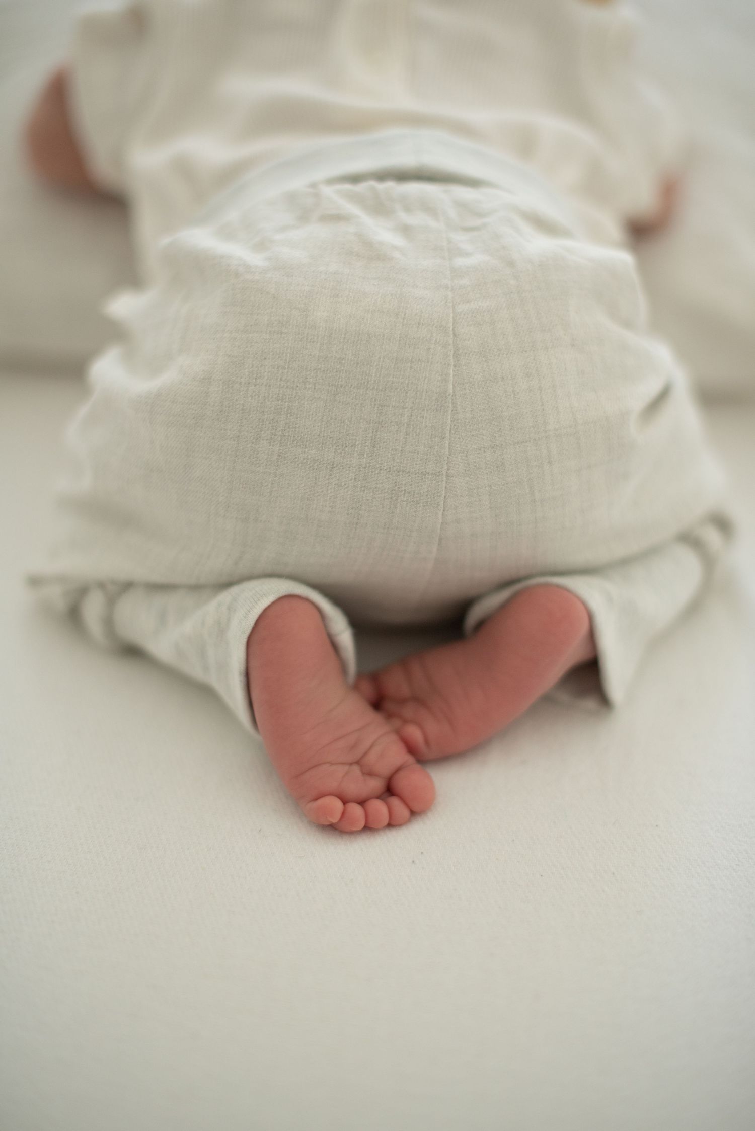 Close-up of tiny baby feet peeking out from linen pants.