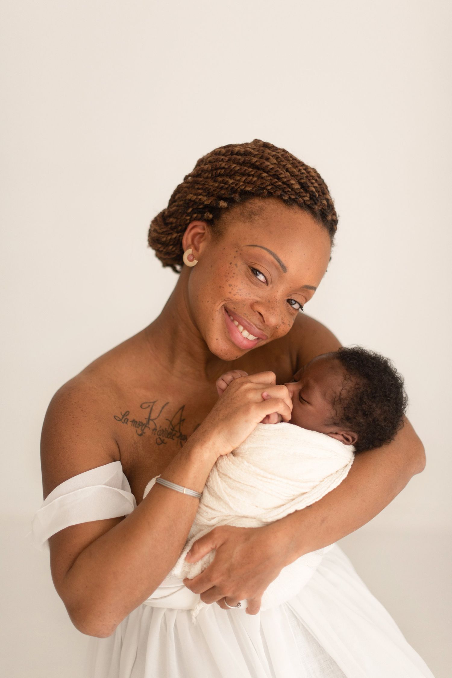 Joyful mother in white dress holding and bonding with newborn baby.