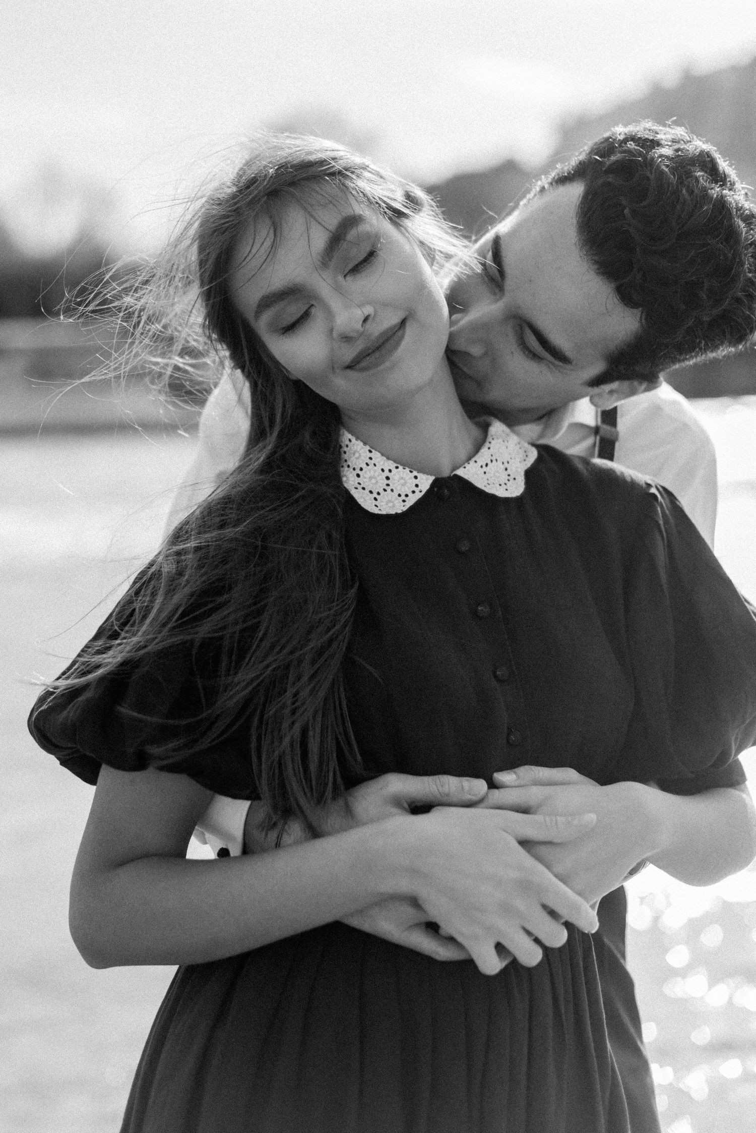 A tender romantic moment captured in black and white with soft backlighting.