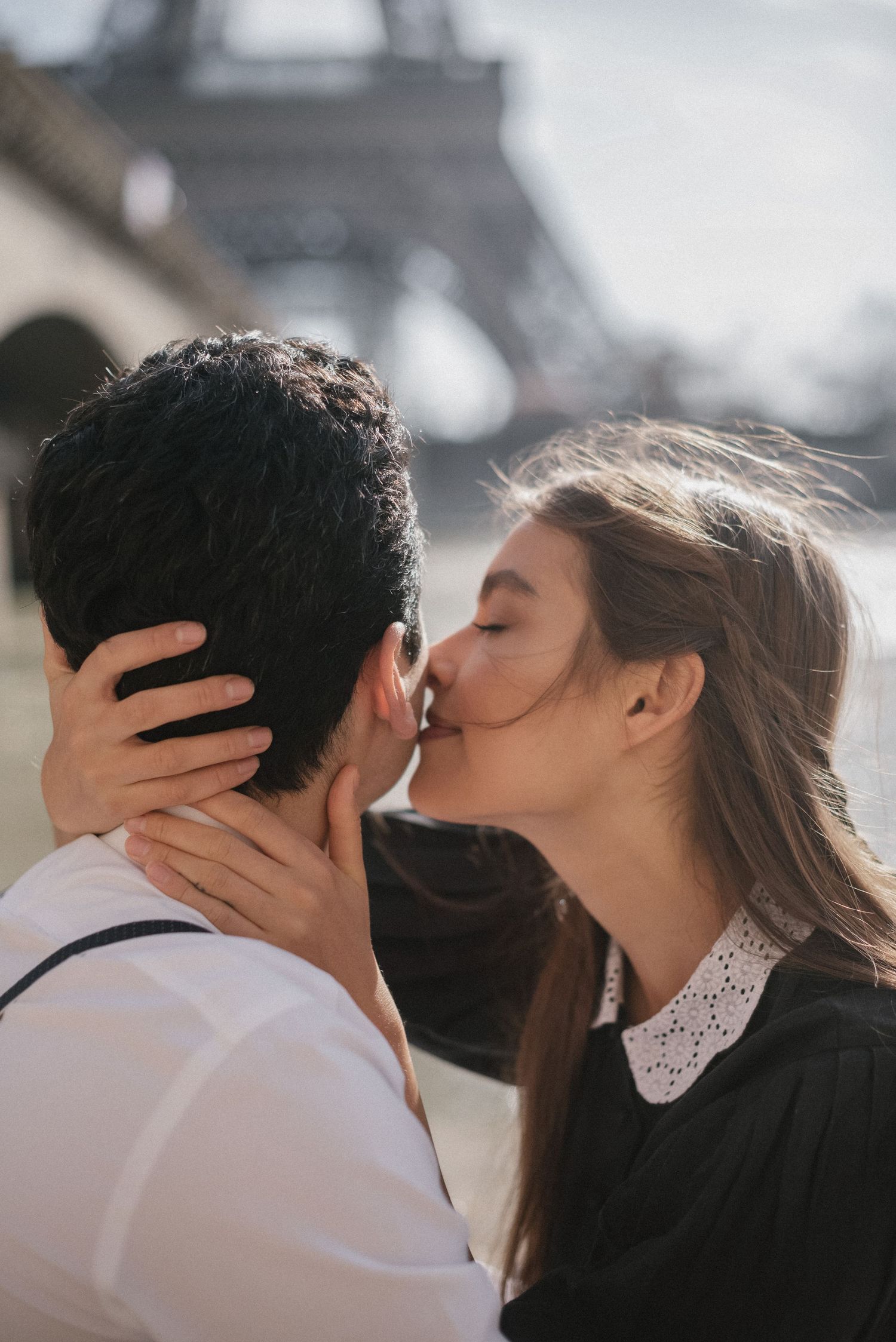A romantic kiss near the Eiffel Tower in Paris with soft lighting.