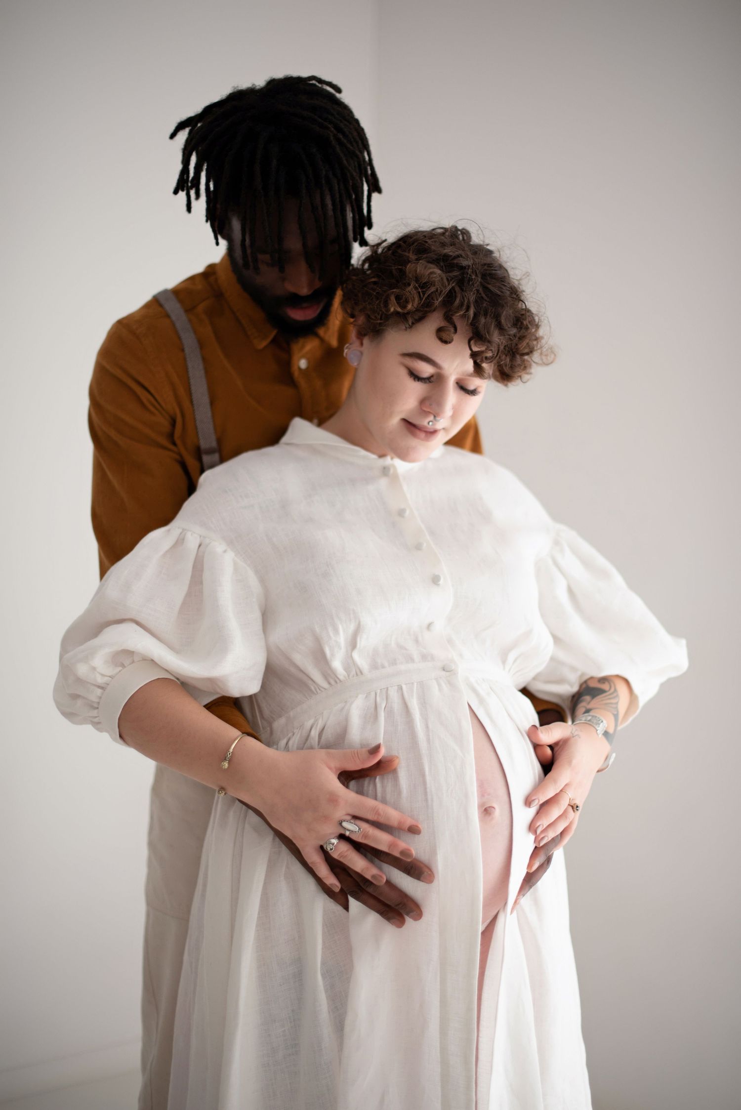 Couple shares intimate moment as they cradle pregnancy bump together.