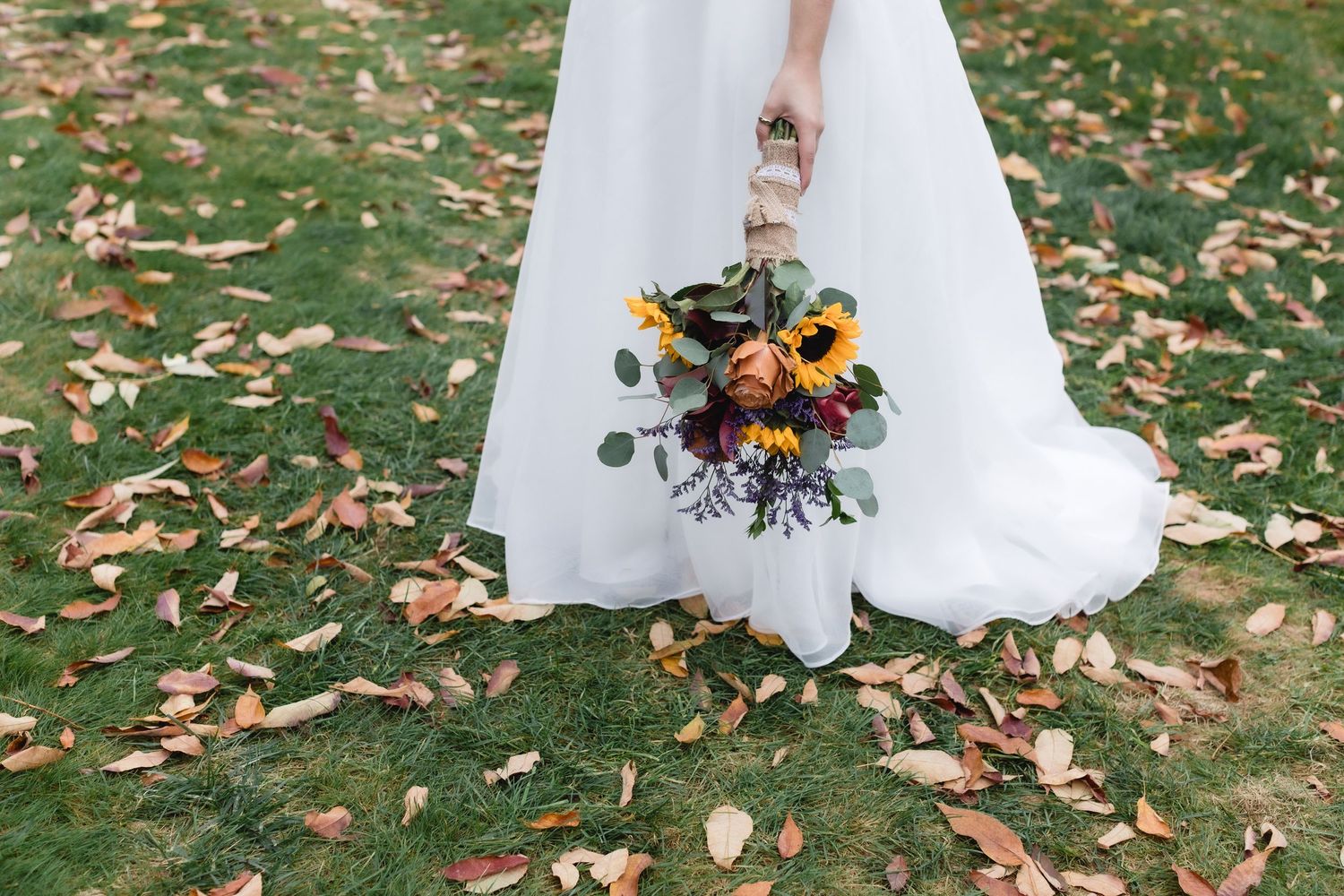 Photo of a bride's wedding dress holding her bouquet of flowers at Westbrook Inn in Derry, New Hampshire. Southern NH wedding photographer.
