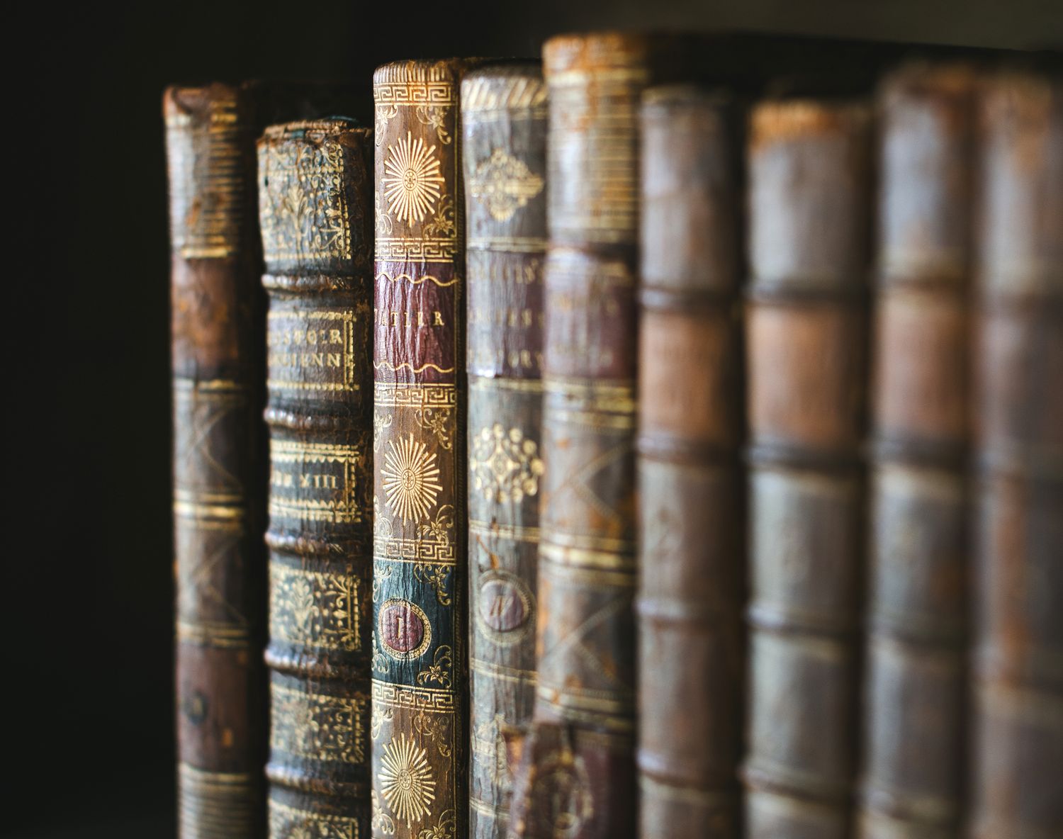 Close up of antique books on a dark shelf at the Fruitlands Museum in Harvard, Massachusetts. Massachusetts photographer