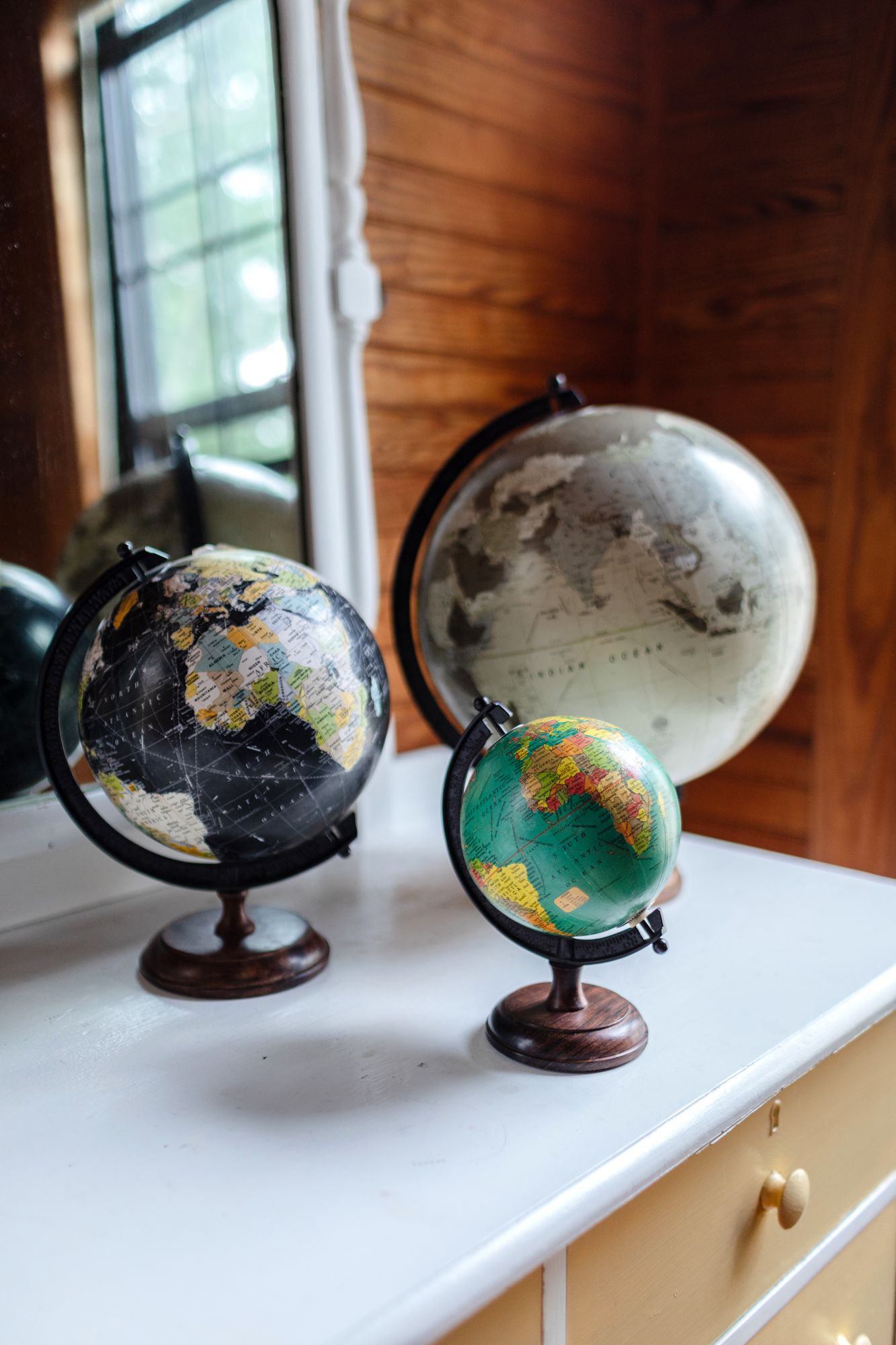 Three antique globes sit on an old painted dresser with oak walls in background. New England New Hampshire photographer