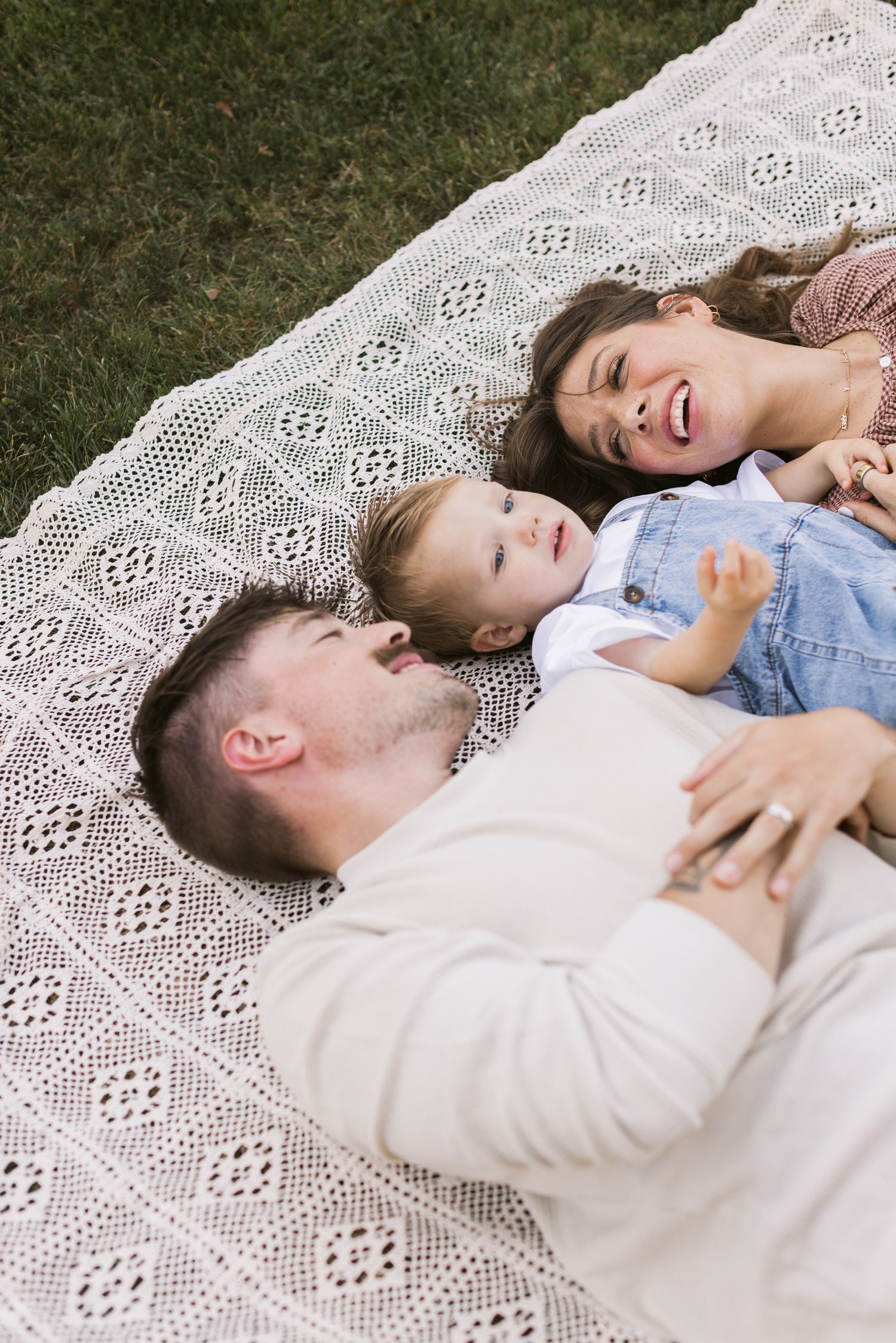 A happy family lays on a crochet blanket for family photos in Stratham, New Hampshire. Seacoast, Lakes Region NH family photographer.