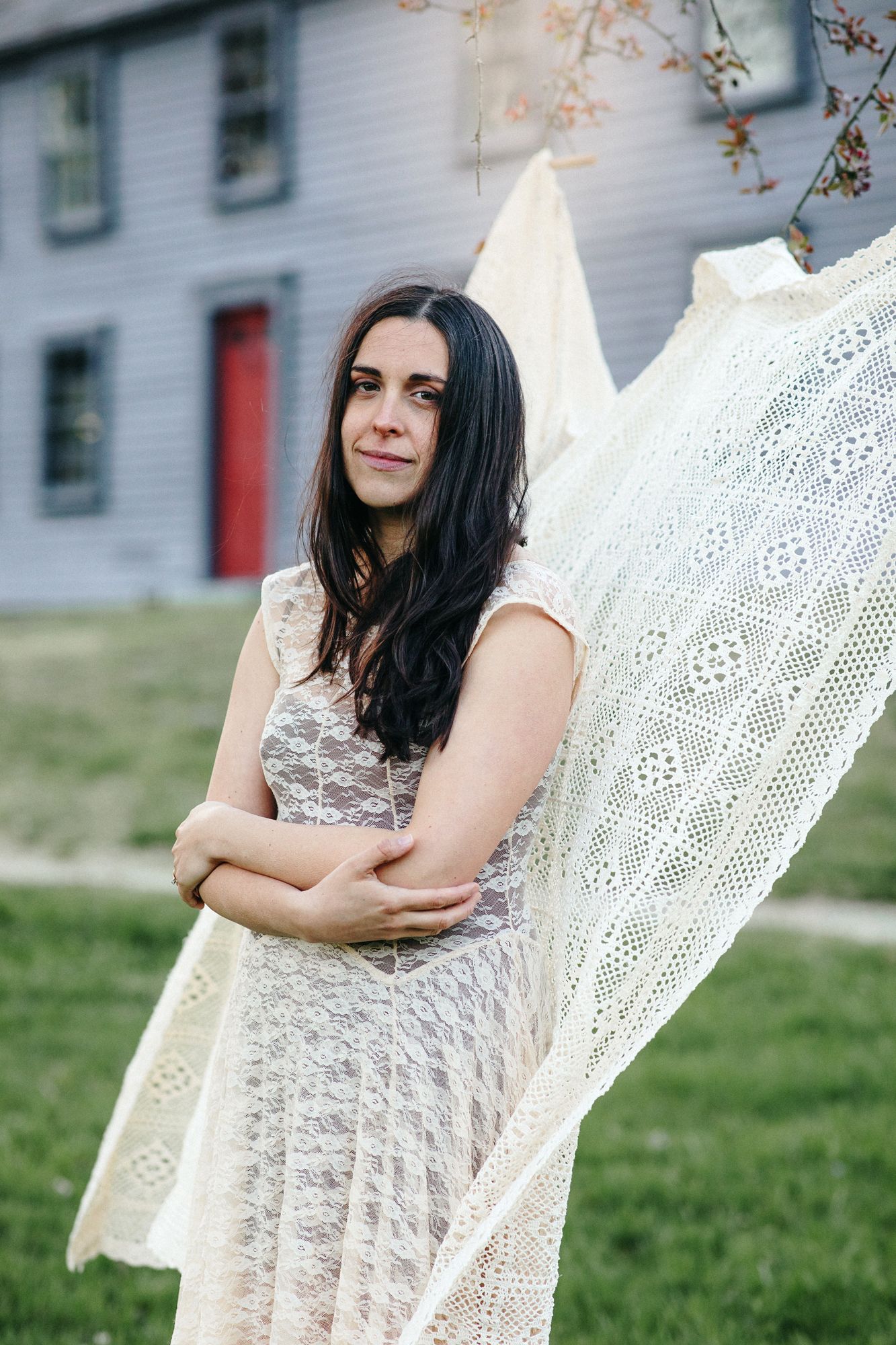Portrait of brown hair mother wearing a cream lace Free People dress in front of Nathan Meriam House in Concord, MA during motherhood photos