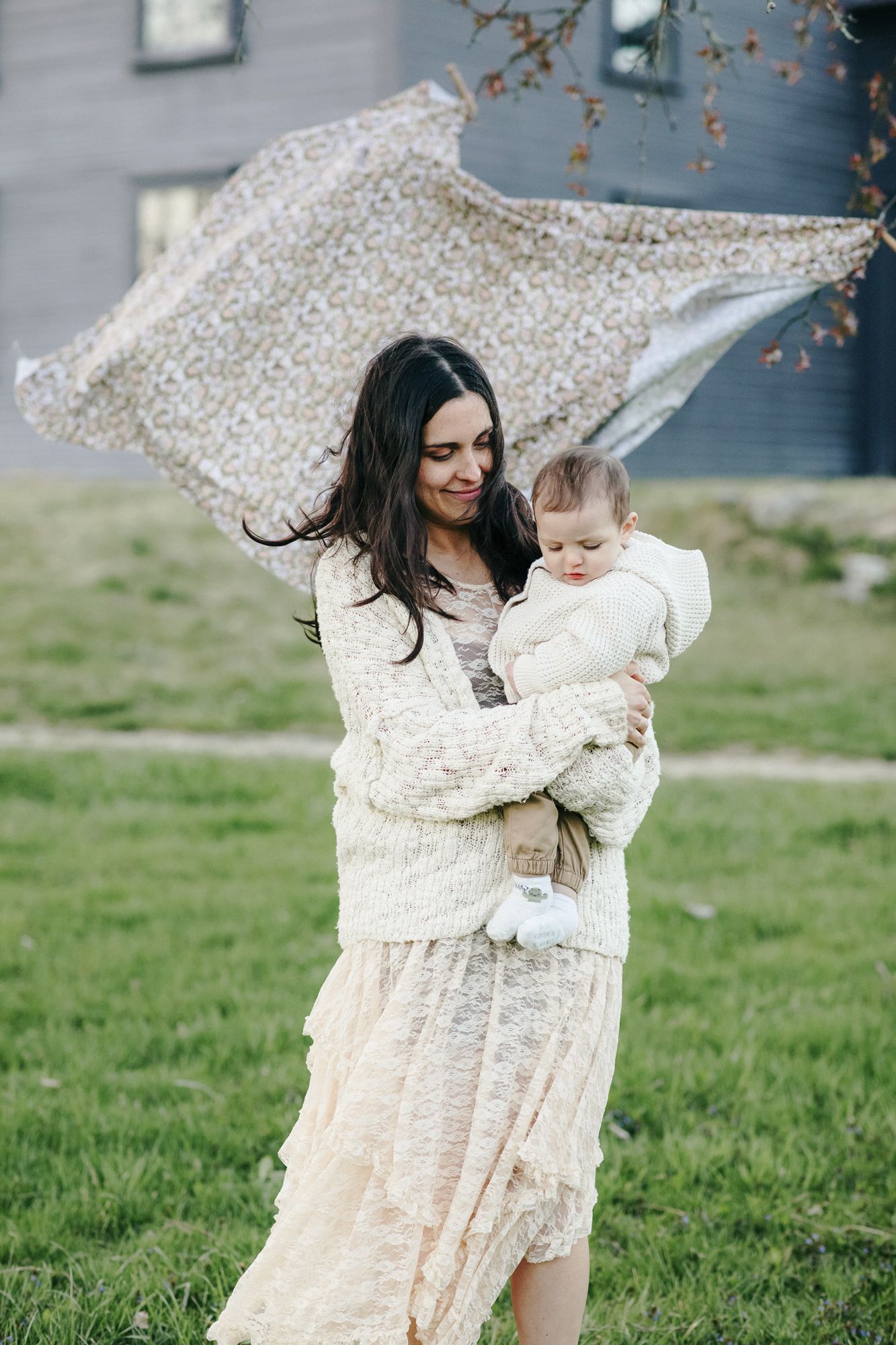 Motherhood photos of mother and five month old son, both wearing cream outfits, in front of Nathan Meriam House in Concord, Massachusetts.