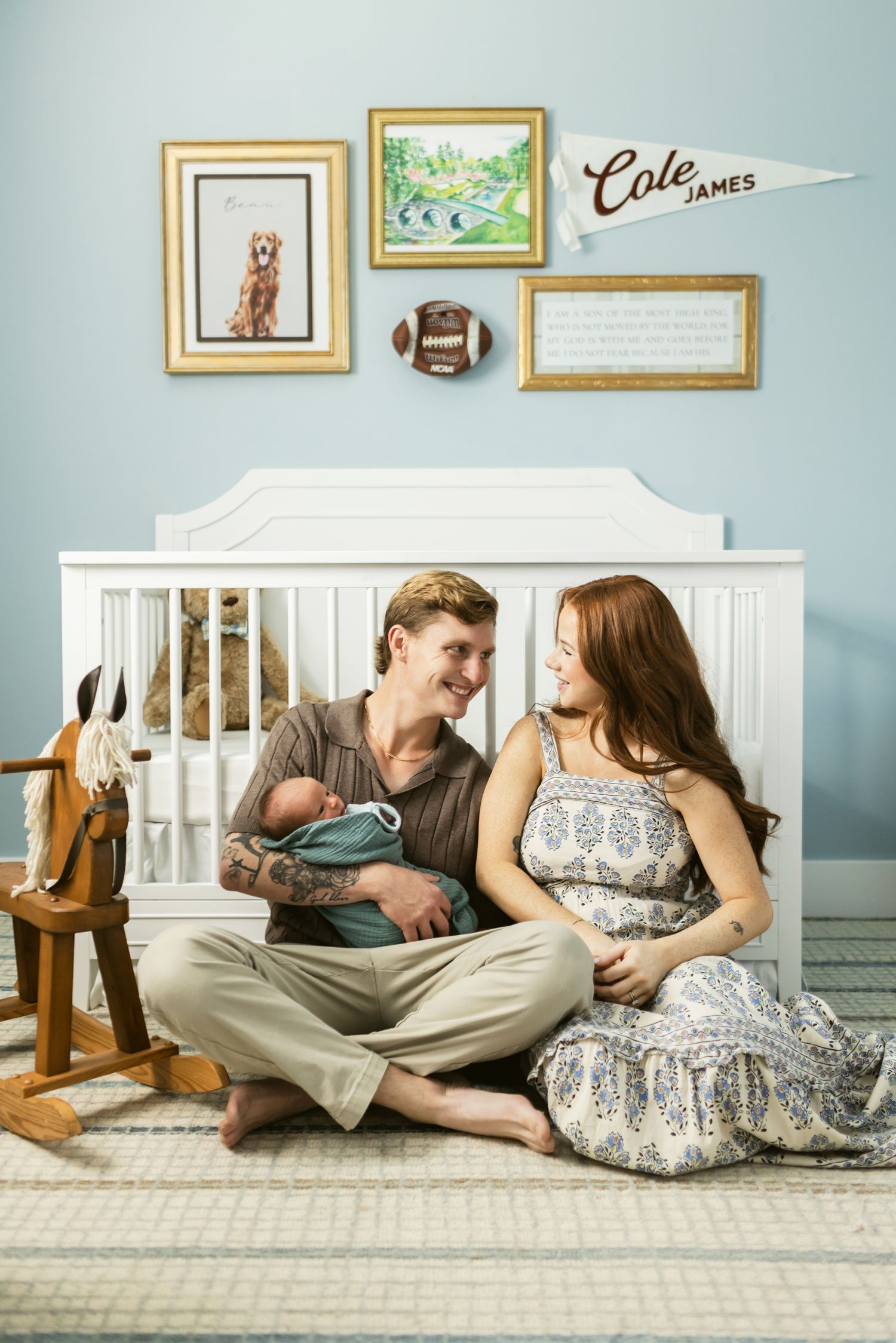 Couple sits in a baby's nursery sits on a rug in front of a white crib for newborn photos in Largo, Florida. Concord newborn photographer