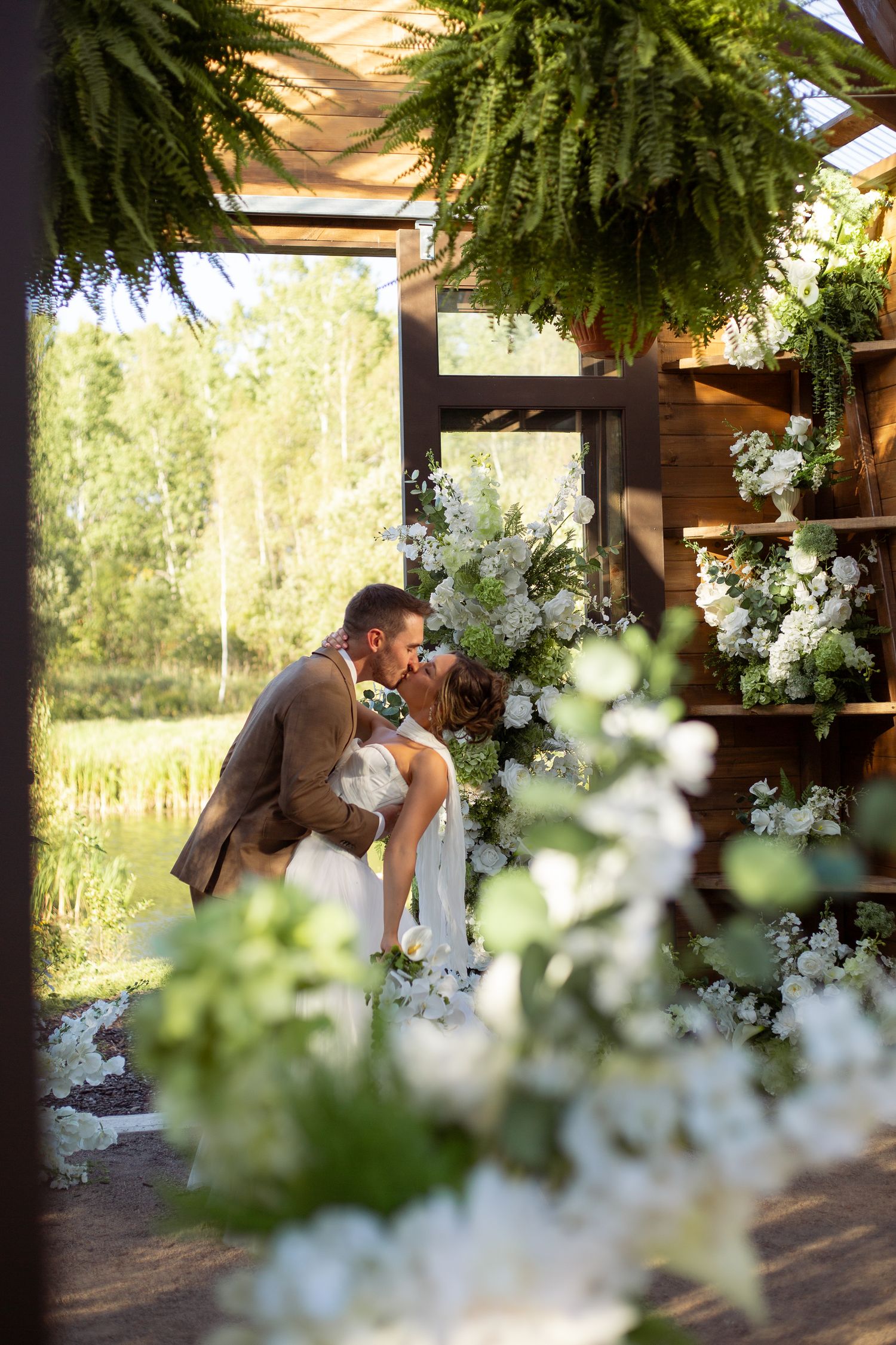 A romantic garden wedding moment surrounded by lush ferns and white flowers in a rustic outdoor setting.
