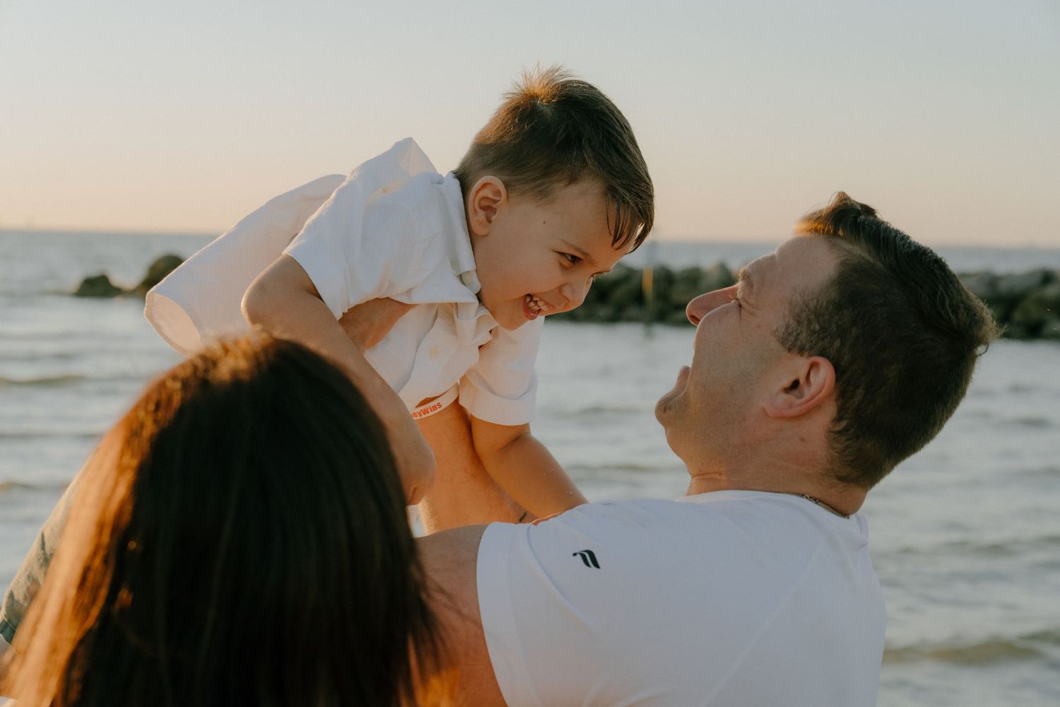 A loving family shares a joyful moment together at sunset on the beach as warm light bathes the scene.