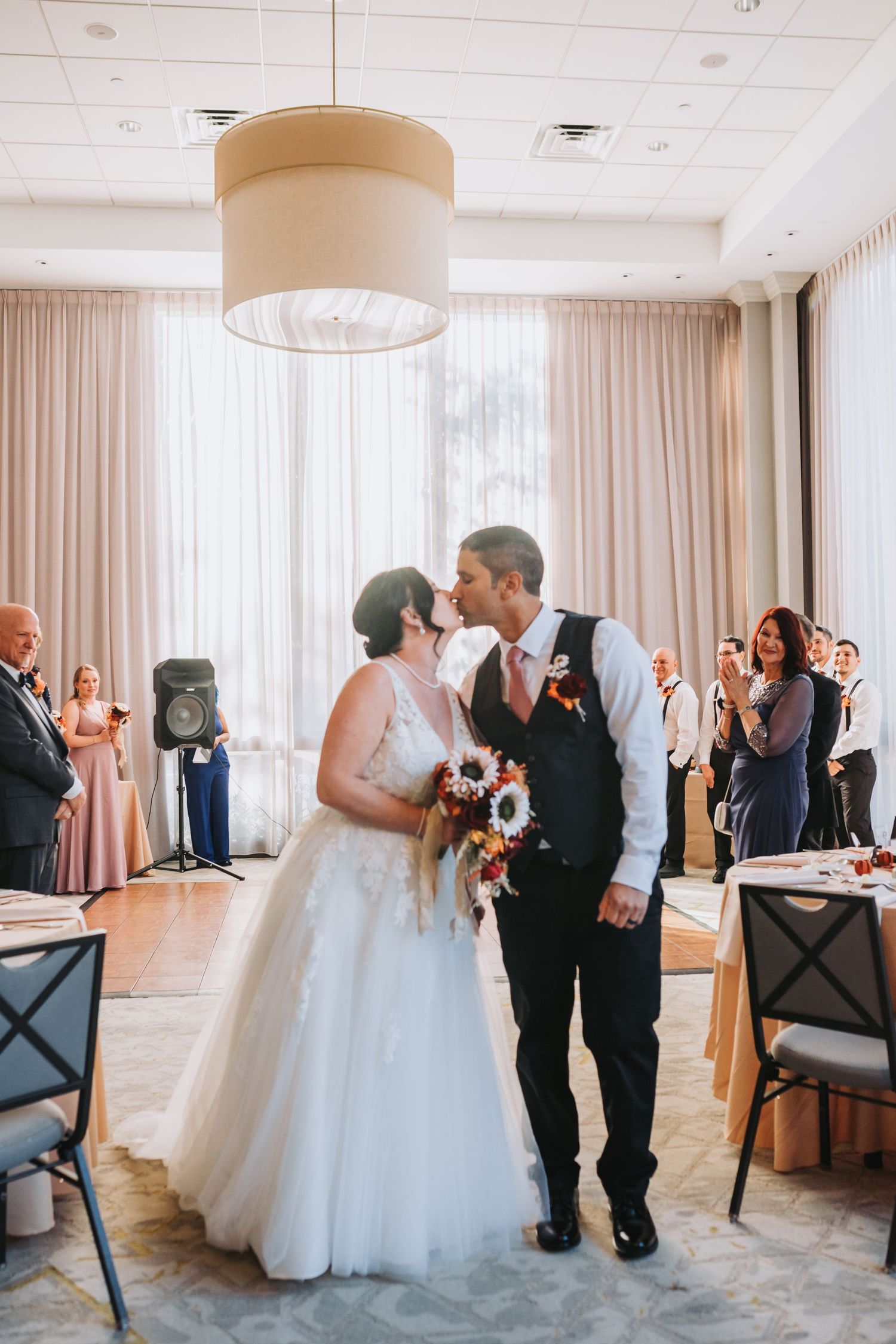 A romantic moment at an indoor wedding reception with a bride in white gown and groom in dark suit under soft lighting.