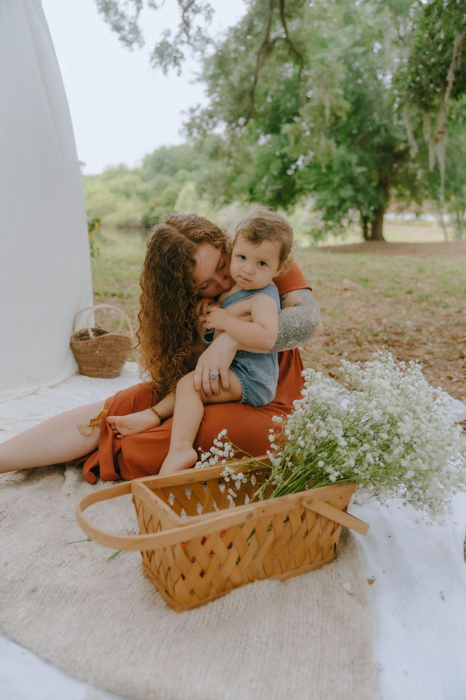 Sweet outdoor scene with delicate baby's breath flowers and rustic woven baskets on a light colored blanket.