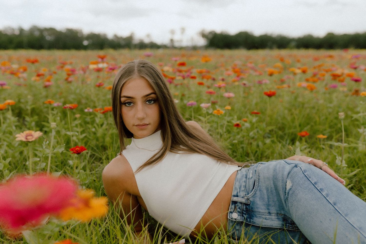 Woman lounging in a vibrant field of red poppies wearing casual summer attire.