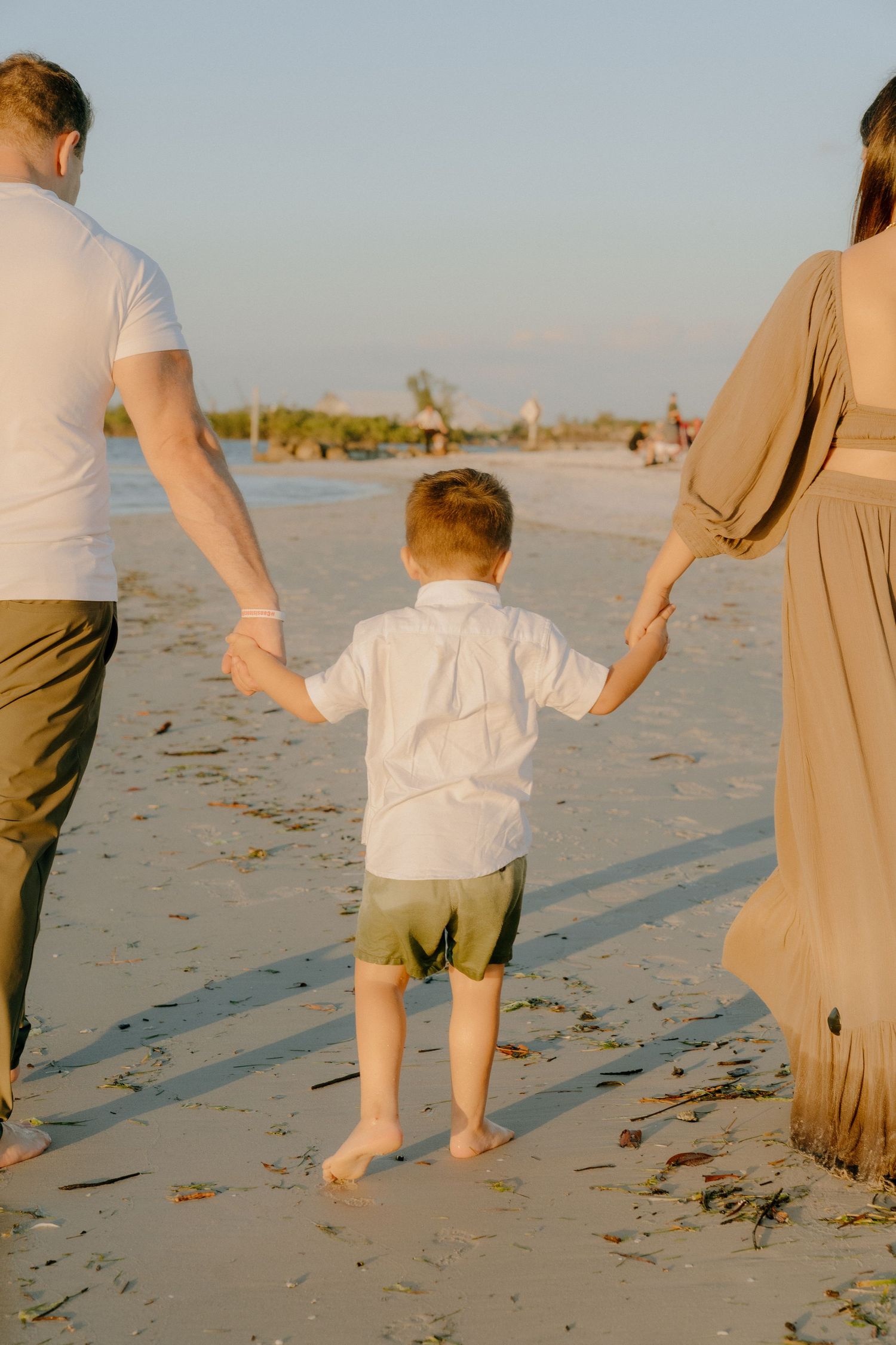 Family enjoying a beach walk together at sunset while holding hands on the sandy shore.