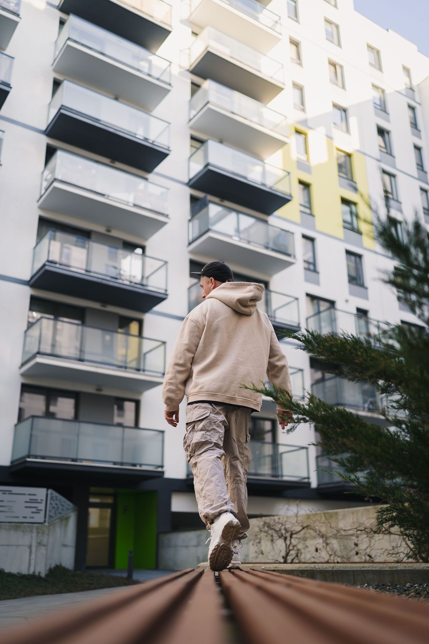 portrait lifestyle photo of man in hip hop dance clothes walks away from camera along a bench