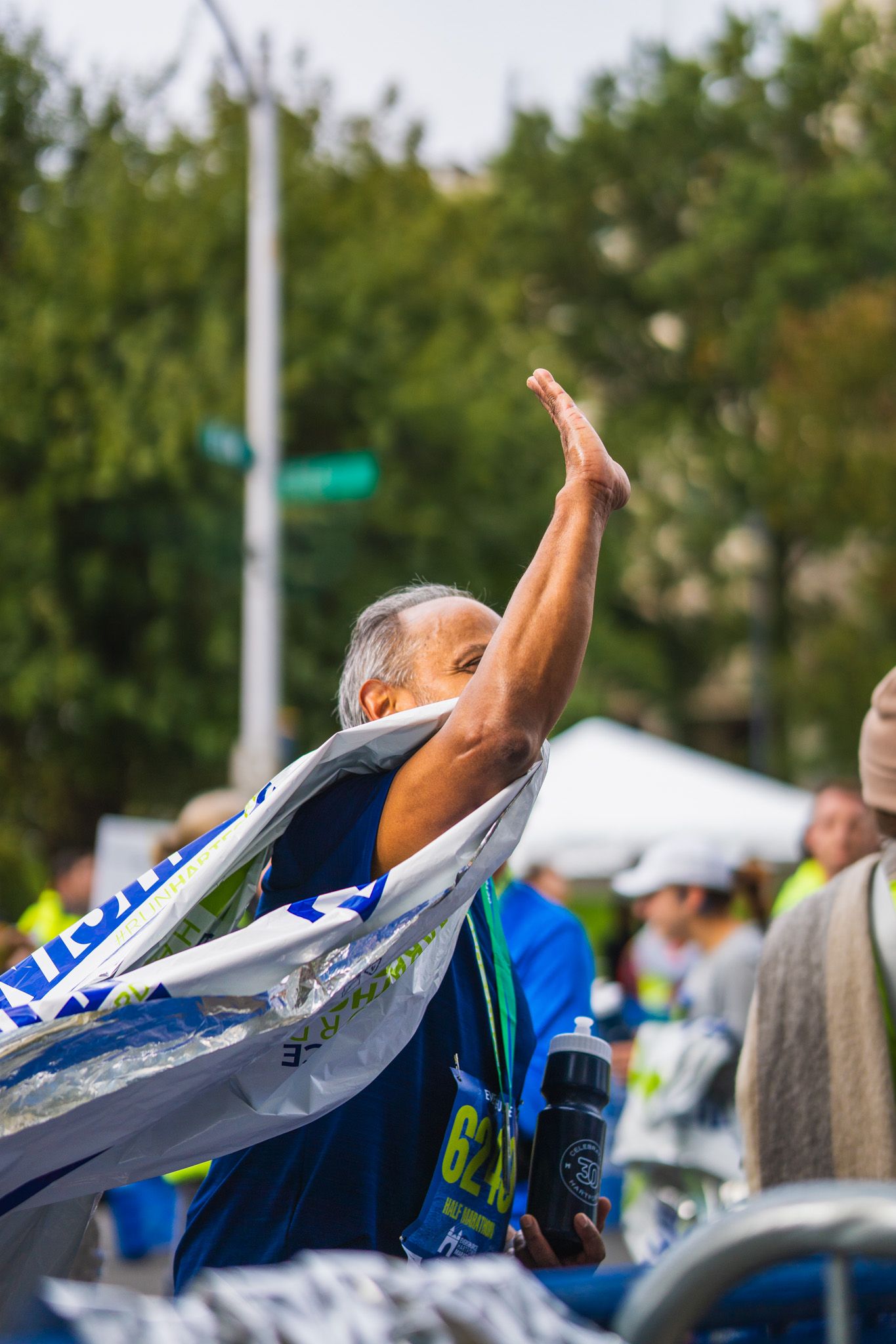 portrait of man at hartford, ct marathon draped in a banner high fiving someone off camera