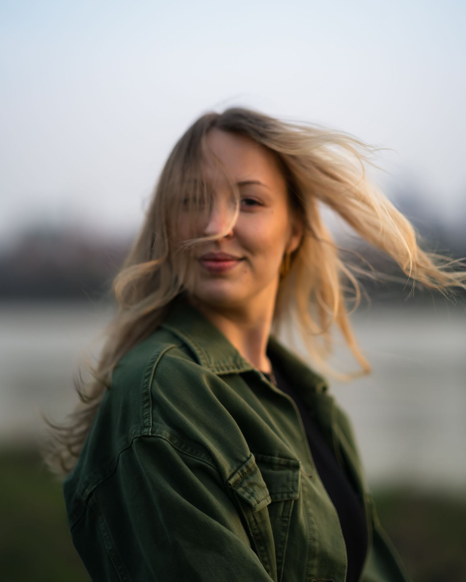 blurry portrait of beautiful blonde woman turning to camera along wisla river in warsaw, poland