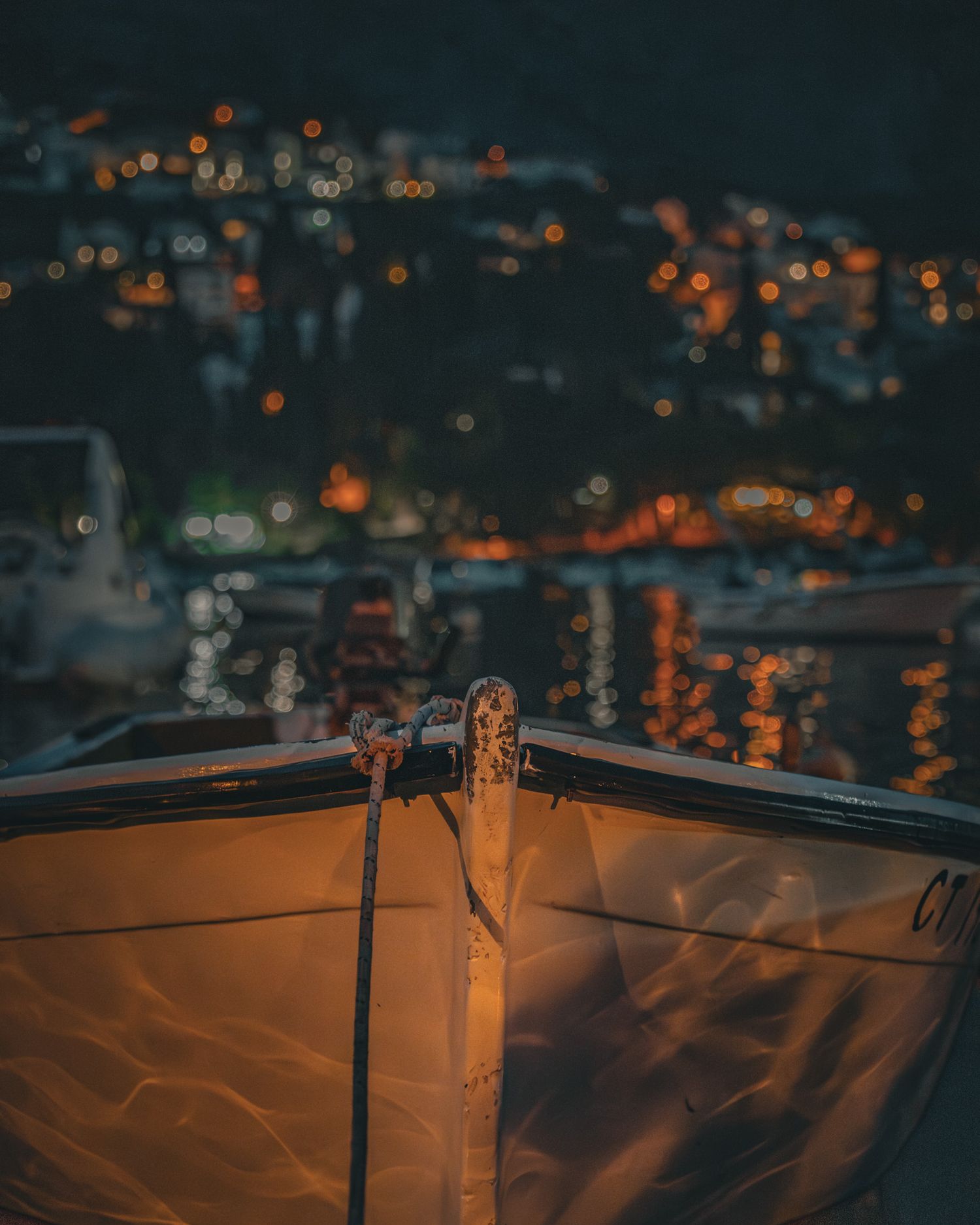 night travel photo of a docked boat in mlini, croatia  with hillside glowing from house lights