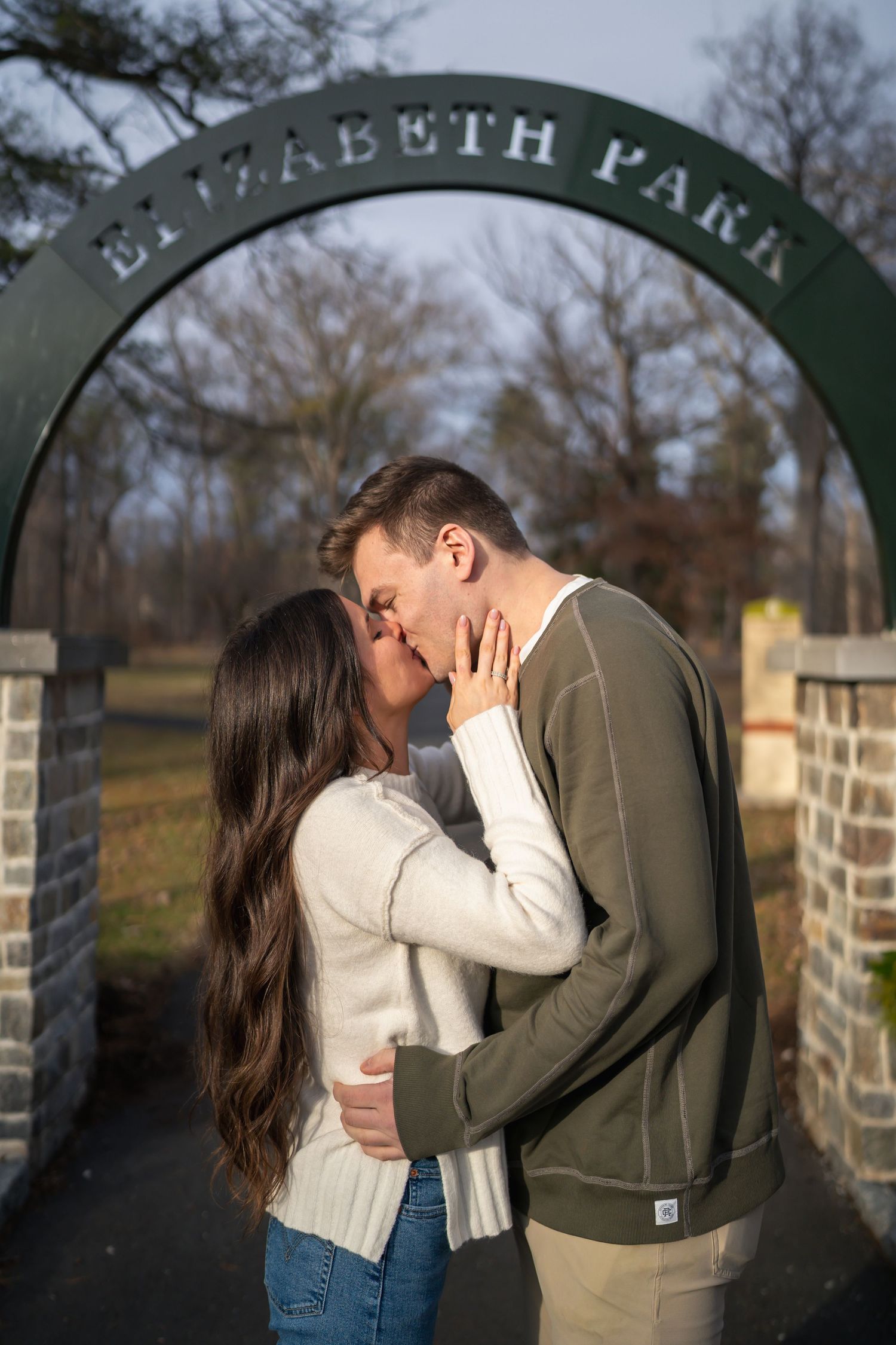 winter engagements photo session in elizabeth park photos of couple kissing at park sign