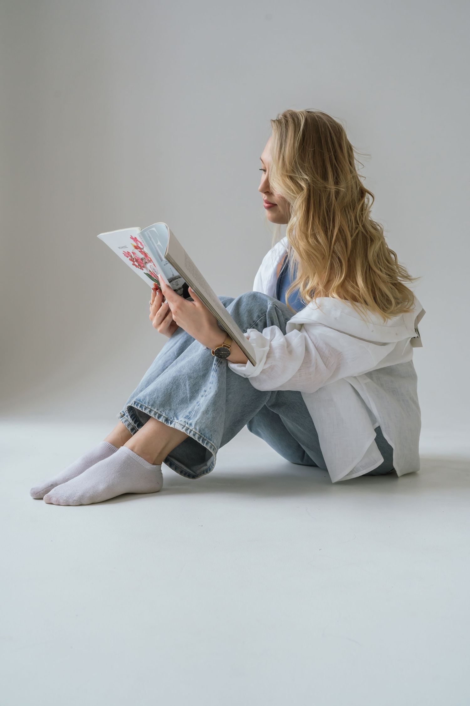 blonde woman reading magazine while sitting in warsaw studio