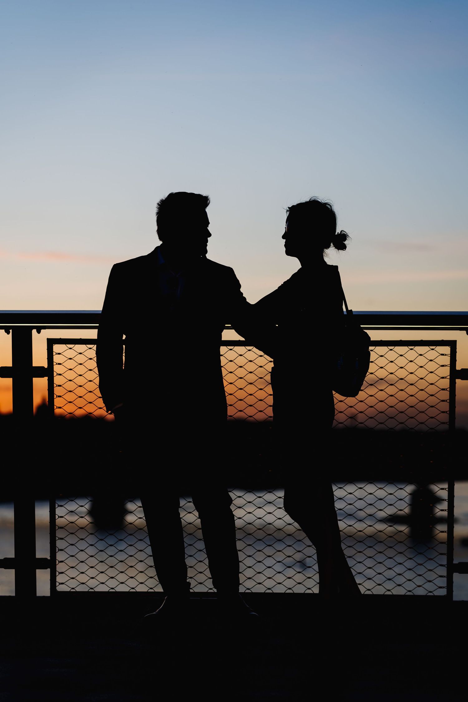 couple portrait holding hands silhouette along the Most Siekierkowski in warsaw, poland at sunset